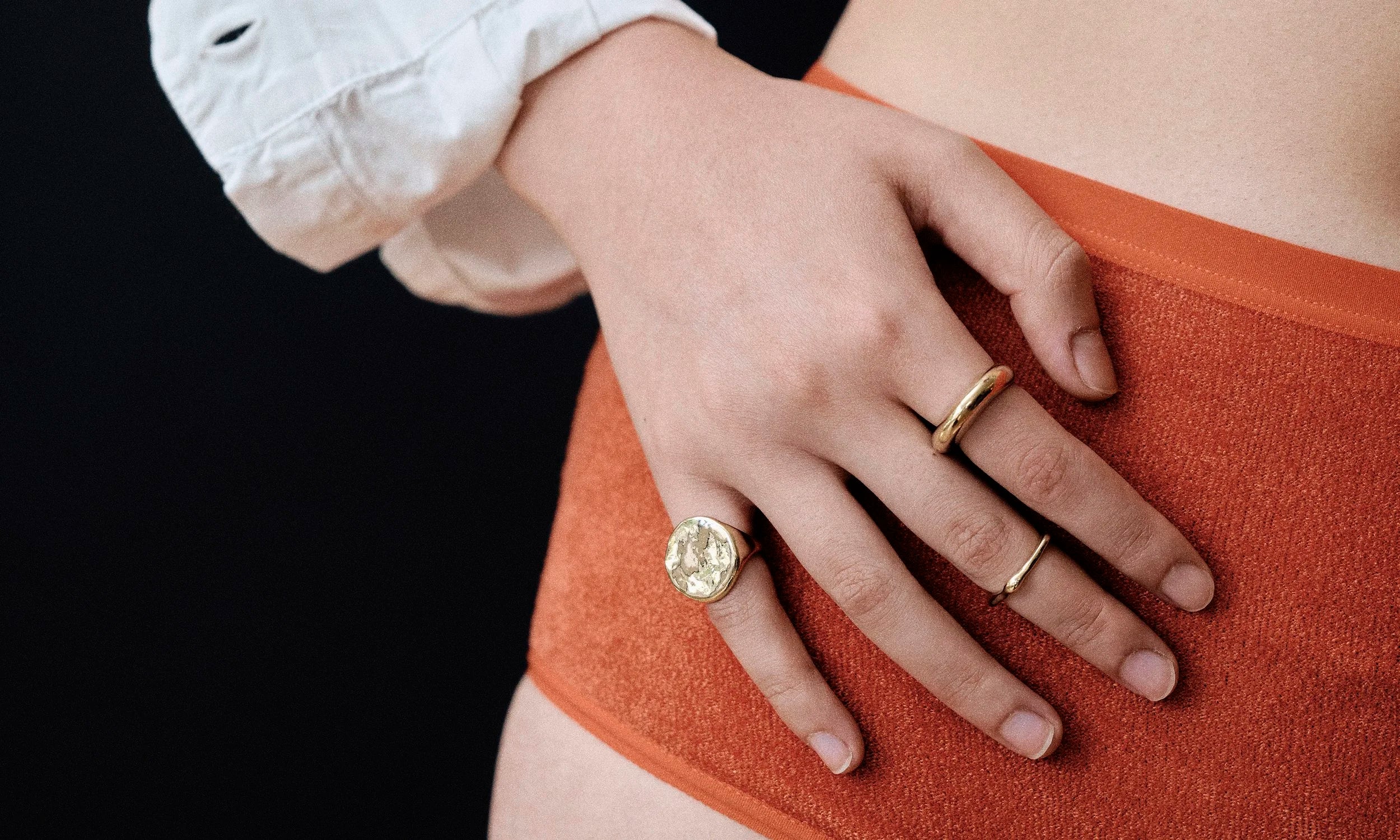 Model Rachel wears the Ra Pinky Signet Ring, Ouroboros Ring, and Persephone Ring. Each piece is hand sculpted and made in solid recycled 14k gold by Talisman Fine Jewelry.