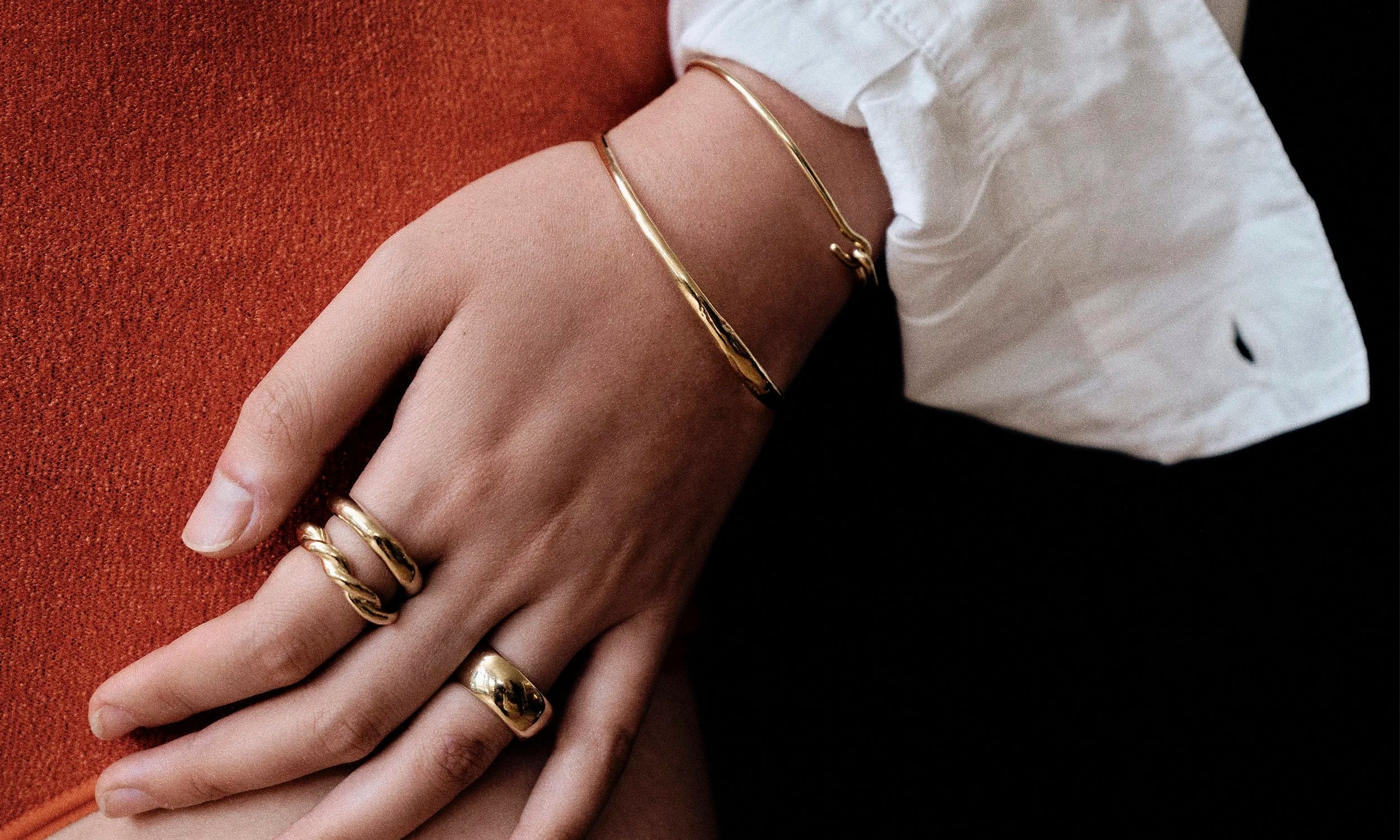Model Rachel wears the Rollo Band Ring, Helix Ring, and Conjunct Cigar Band paired with the Portal Bracelet and Orbit Bracelet. All sustainably handmade in solid recycled 14k gold by Talisman Fine Jewelry.