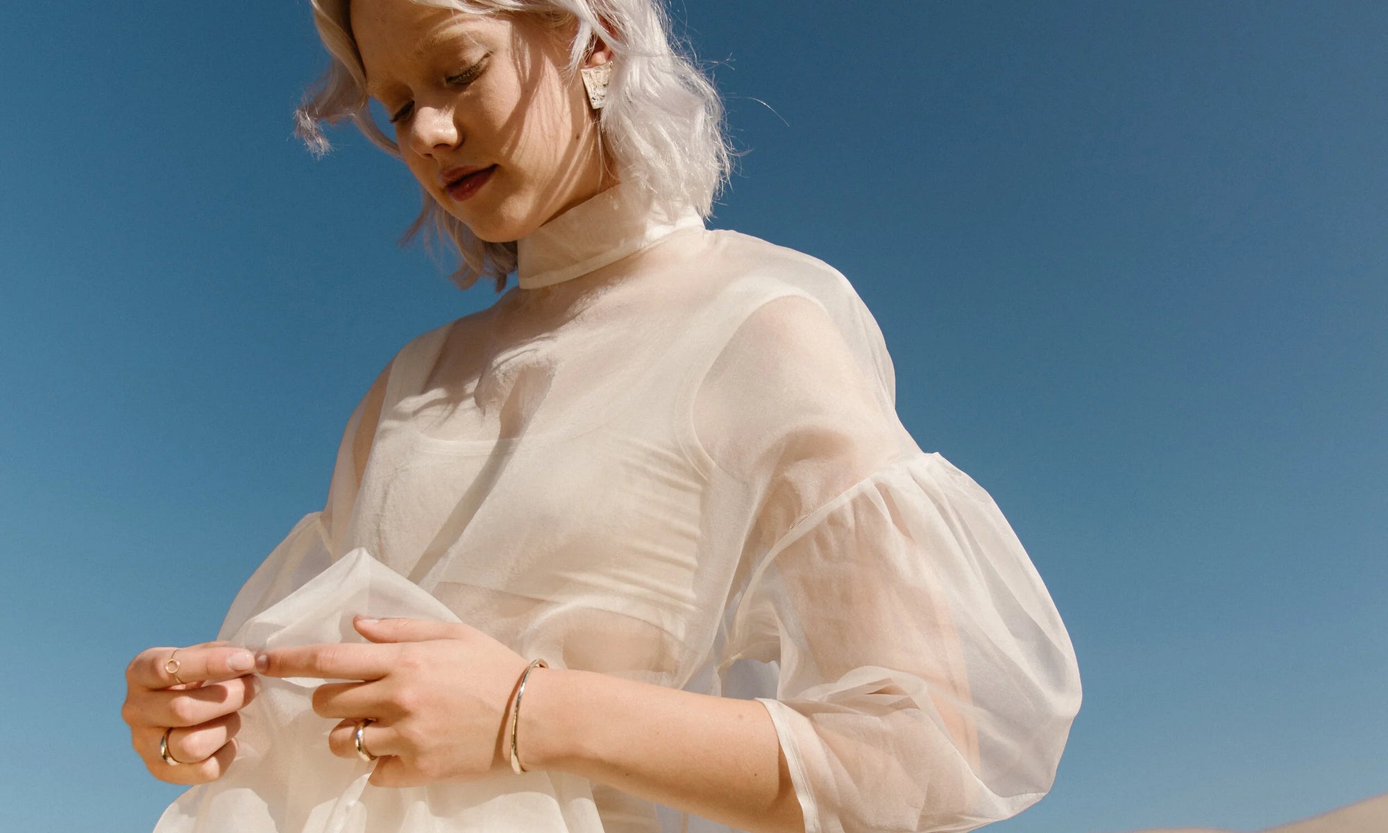 Model Aleah Hyvonen wears the Plane Earrings, Portal Bracelet, Circle Shape Ring, Portal Ring, and Rollo Band. All sustainably handmade in recycled 14k gold using traditional lost-wax casting techniques.