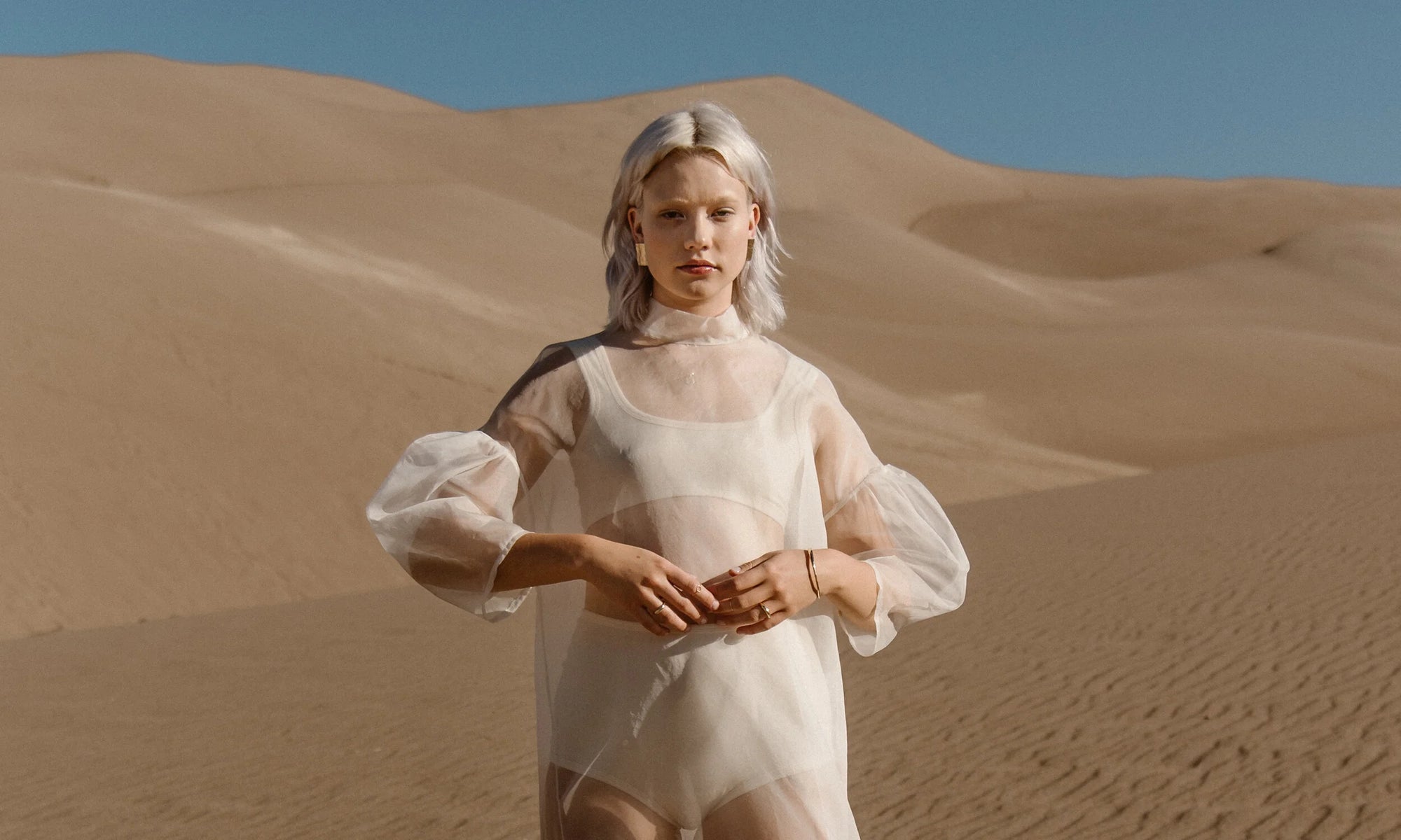 Model Aleah Hyvonen wears the Plane Earrings, Michael Amulet Necklace, Whisper Chain, Portal Bracelet, Portal Ring, and Rollo Band. All sustainably handmade in recycled 14k gold using traditional lost-wax casting techniques.