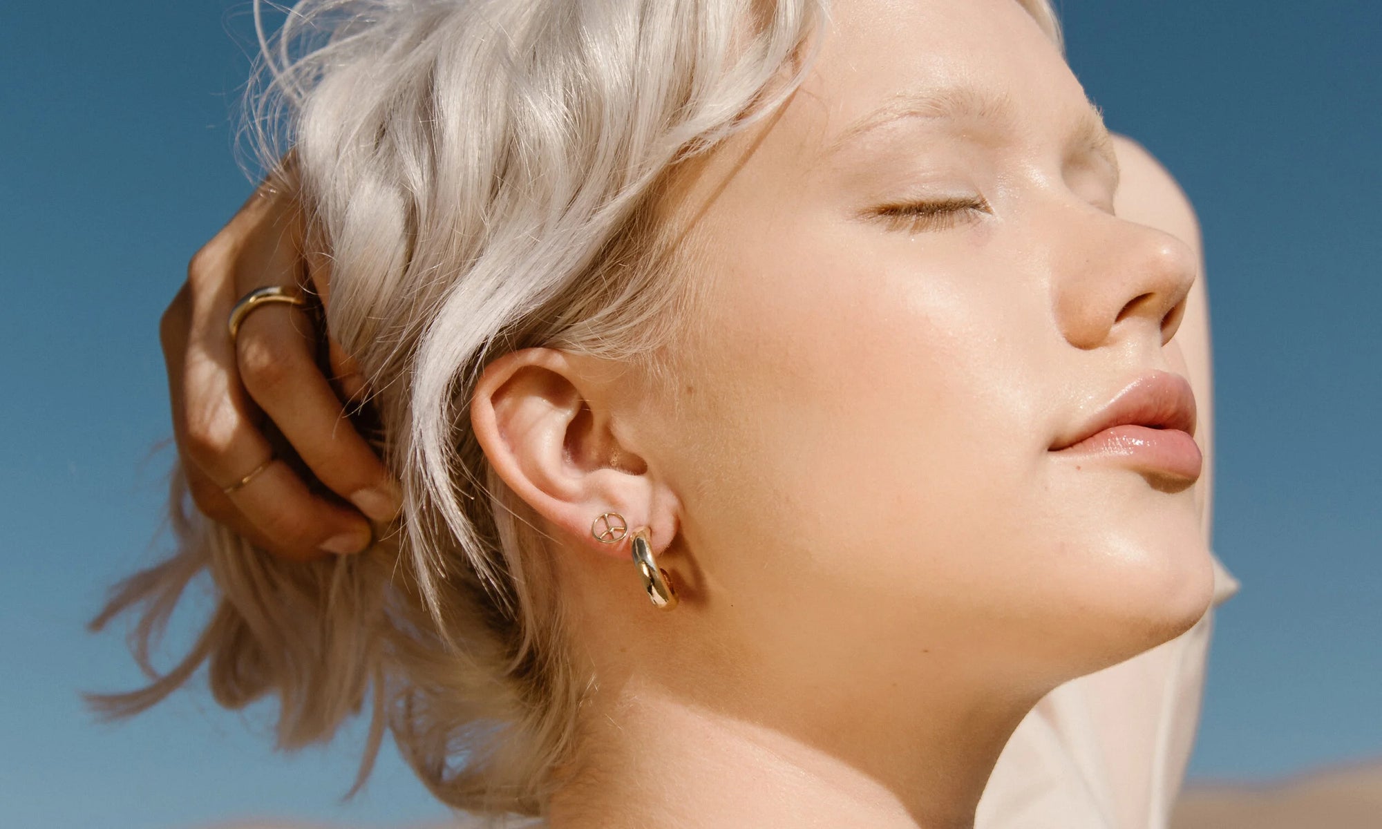 Aleah Hyvonen wears the Rollo Hoops, Peace Sign Stud, and Rollo Band and Goldyn Hammered Stacking Band. All sustainably handmade in recycled 14k gold, using traditional lost-wax casting techniques.