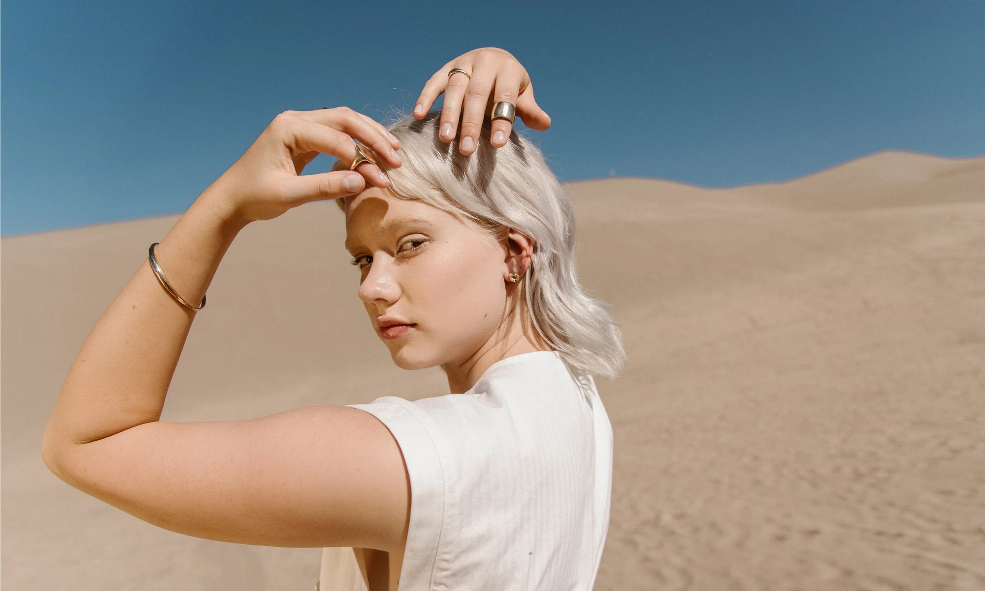 Model Aleah Hyvonen wears the Portal Bracelet, Ra Signet Ring, Portal Ring, Demeter Cigar Band, and Central Sun Earrings. All sustainably handmade in recycled 14k gold, using traditional lost-wax casting techniques.
