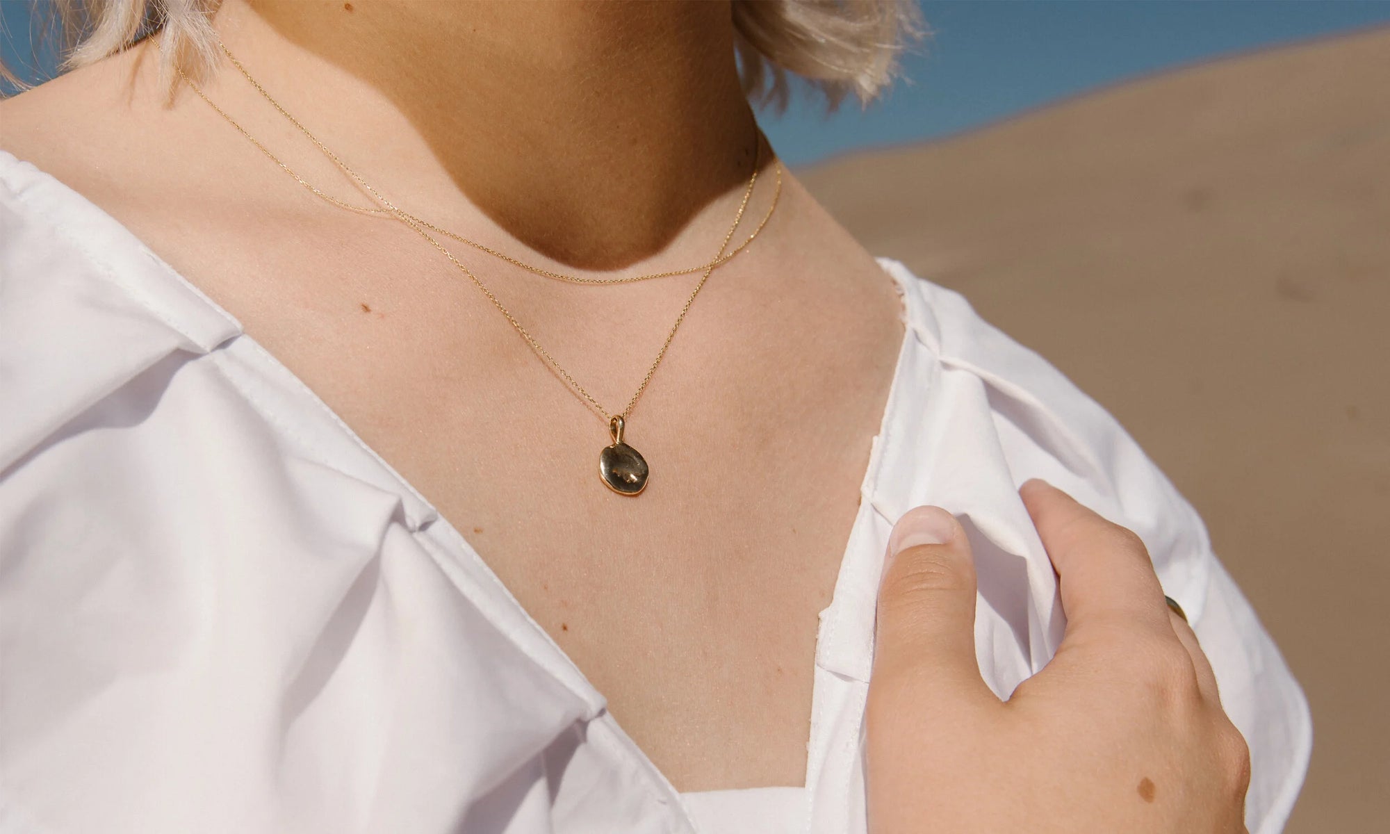 Model Aleah Hyvonen wears the Michael Amulet Necklace and Whisper Chain. The Michael Amulet is sustainably handmade in recycled 14k gold, using traditional lost-wax casting techniques.