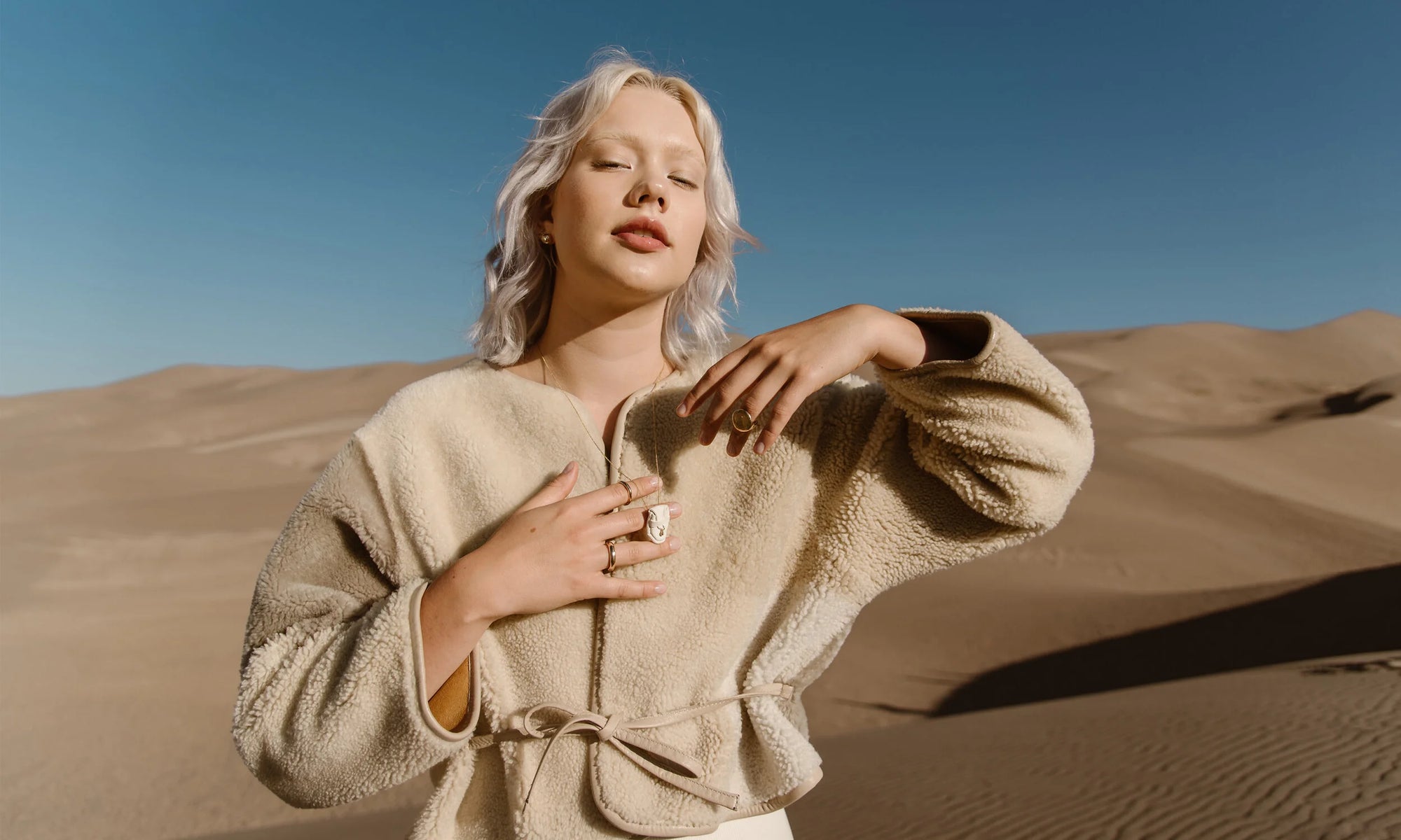 Model Aleah Hyvonen wears the Central Sun Earrings, Spiral Stud, Wave Stud, and Mini Orb Stud, along with the Brilliant Diamond Talisman Pouch Necklace, and the Petite Rollo Band, Rollo Band, and Ra Signet Ring. All sustainably handmade in recycled 14k gold, using traditional lost-wax casting techniques.