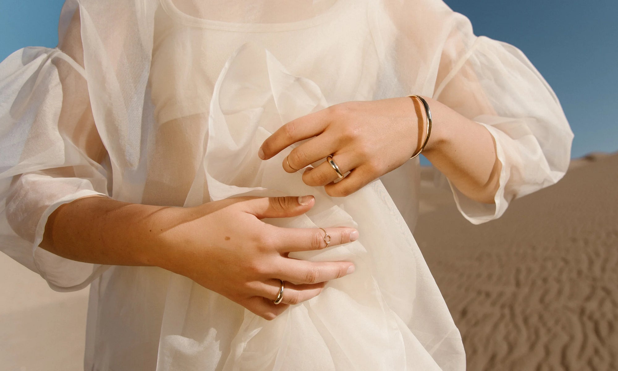 Model Aleah Hyvonen wears the Portal Bracelet, Goldyn Hammered Stacking Ring, Rollo Band, Circle Shape Ring and Portal Ring. All sustainably handmade in recycled 14k gold using traditional lost-wax casting techniques.