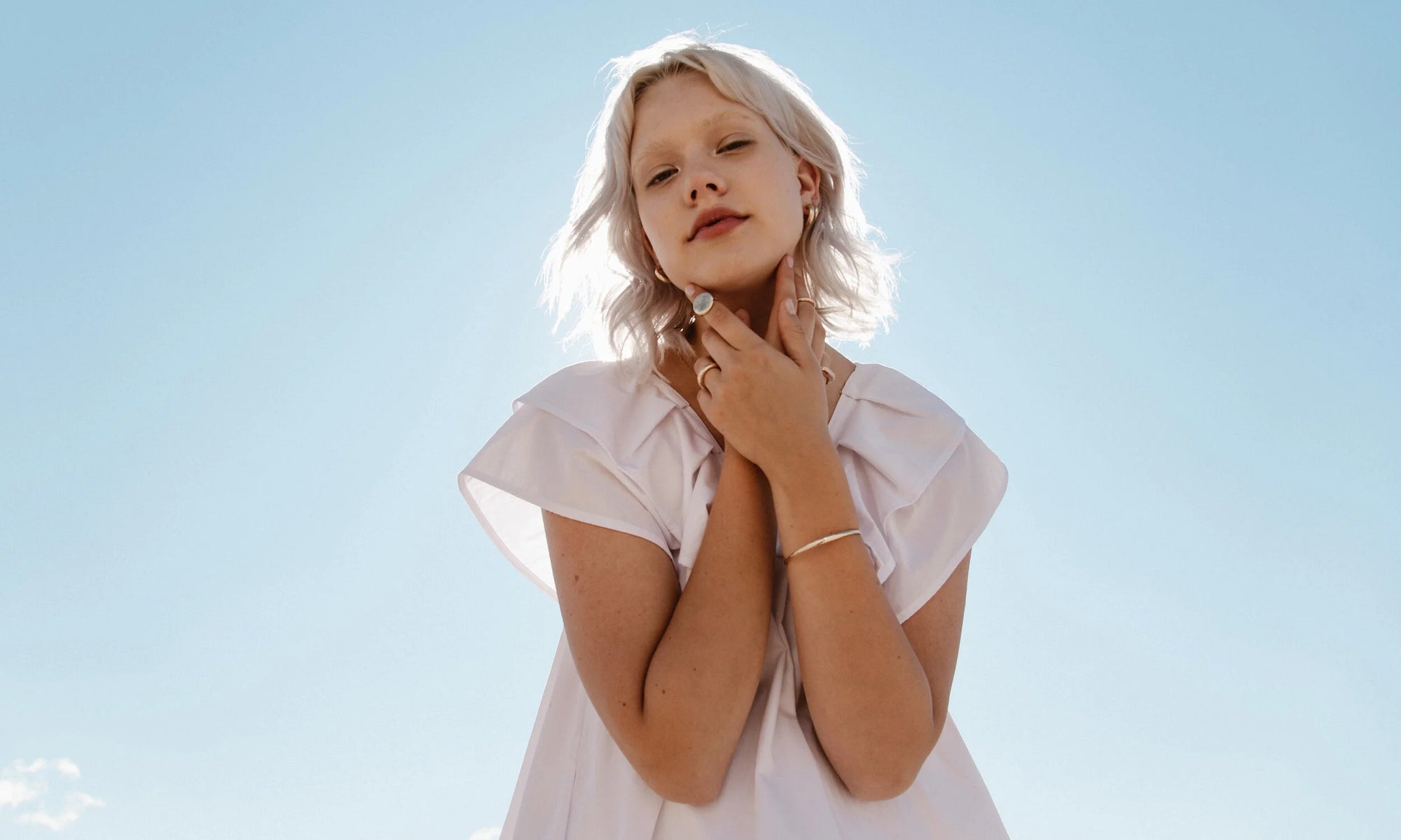 Model Aleah Hyvonen wears the Rollo Hoops, Aphrodite Hugs, and Mini Rainbow Stud, along with the Michael Amulet Necklace and Whisper Chain, and the Persephone Ring, Petite Rollo Band, Ra Signet, Rollo Band, and Portal Bracelet. All sustainably handmade in recycled 14k gold, using traditional lost-wax casting techniques.