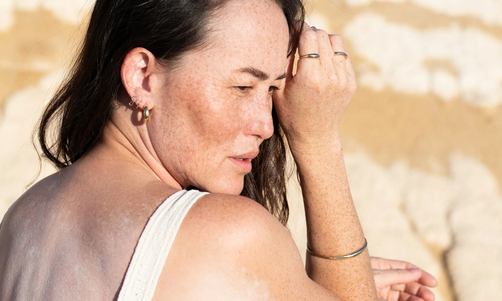 Sunshine wears, from left: The Shroom Stud, U Earring, and Rollo Hoop, along with the Portal Ring, Sirius B Ring, Petite Rollo Band, and Portal Bracelet. All sustainably handmade in recycled 14k gold.