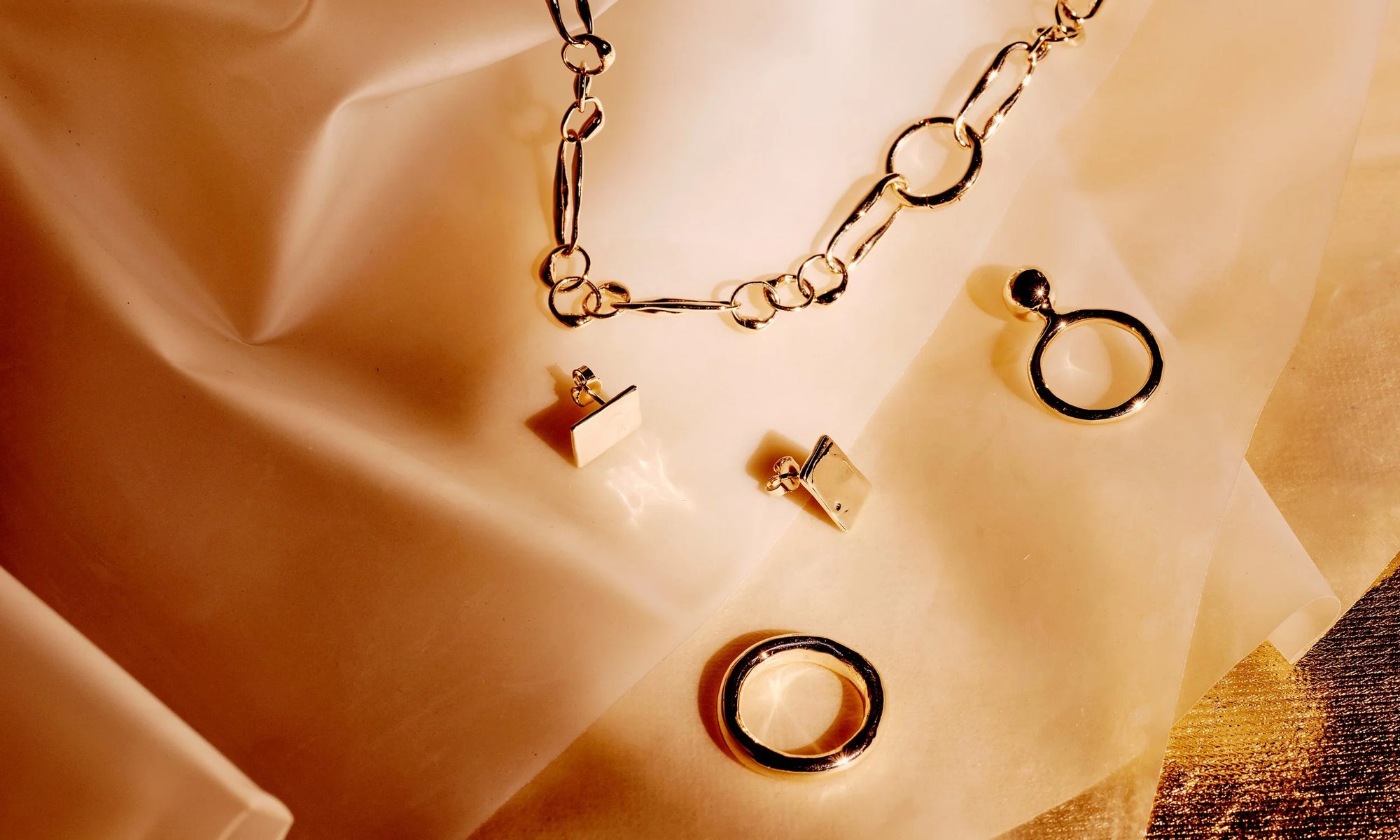 Handmade the old school, analog way in recycled 14k gold, Talisman's jewelry are sculptural heirlooms to last a lifetime. Clockwise from top: the Metanoia Handmade Chain, new Central Sun Ring, Rollo Band, and the Petite Plane Earrings.
