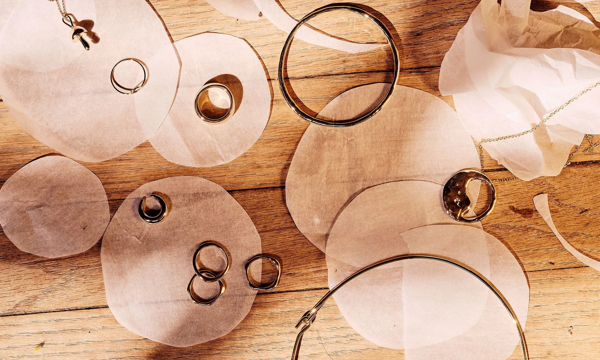 Recycled 14k gold jewels glow in the morning light alongside clippings by artist Erin McAllister, at her studio in the Evans School. Items include, clockwise from top left: Shroom Necklace, Circle Ring, Conjunct Cigar Band, Portal Bracelet, Yin Yang Necklace, Orbit Collar, Sirius C Ring, Conjunct Ring, Sirius B Ring, and the Delphi Ear Cuff.