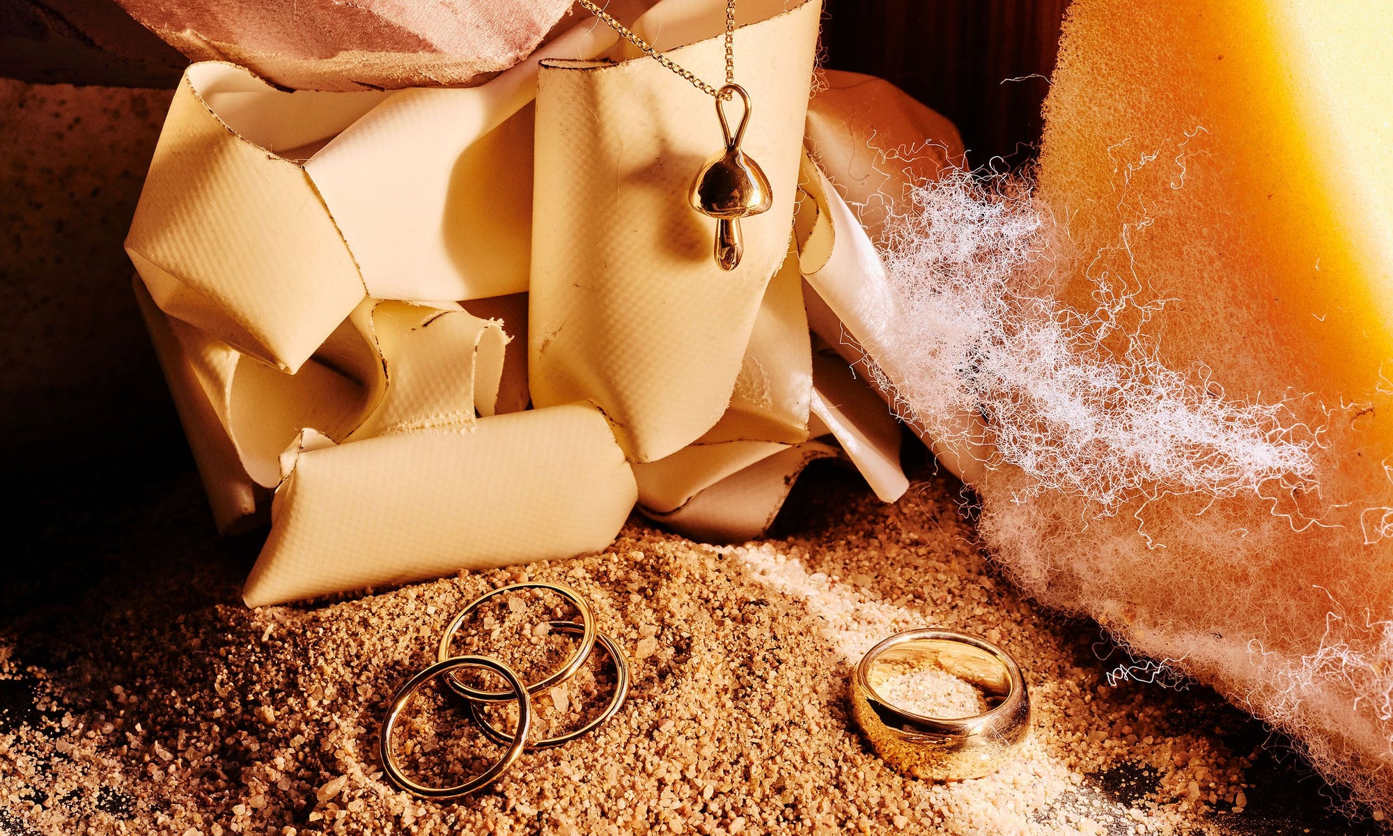 Handmade the old school, analog way, each Talisman piece is sustainably crafted from recycled 14k gold. Clockwise from top: the Shroom Necklace, Conjunct Cigar Band, and the Infinite Ring Stack.
