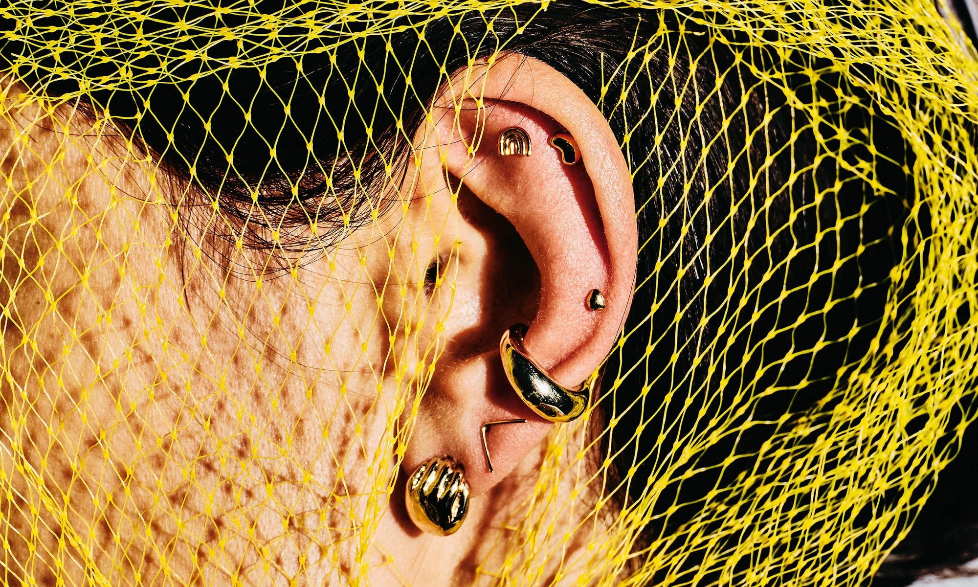 Vanessa Luka wears the Held Earrings, V Stud, Delphi Ear Cuff, Mini Orb Studs, and Mini Rainbow Stud. All sustainably handmade in recycled 14k gold.