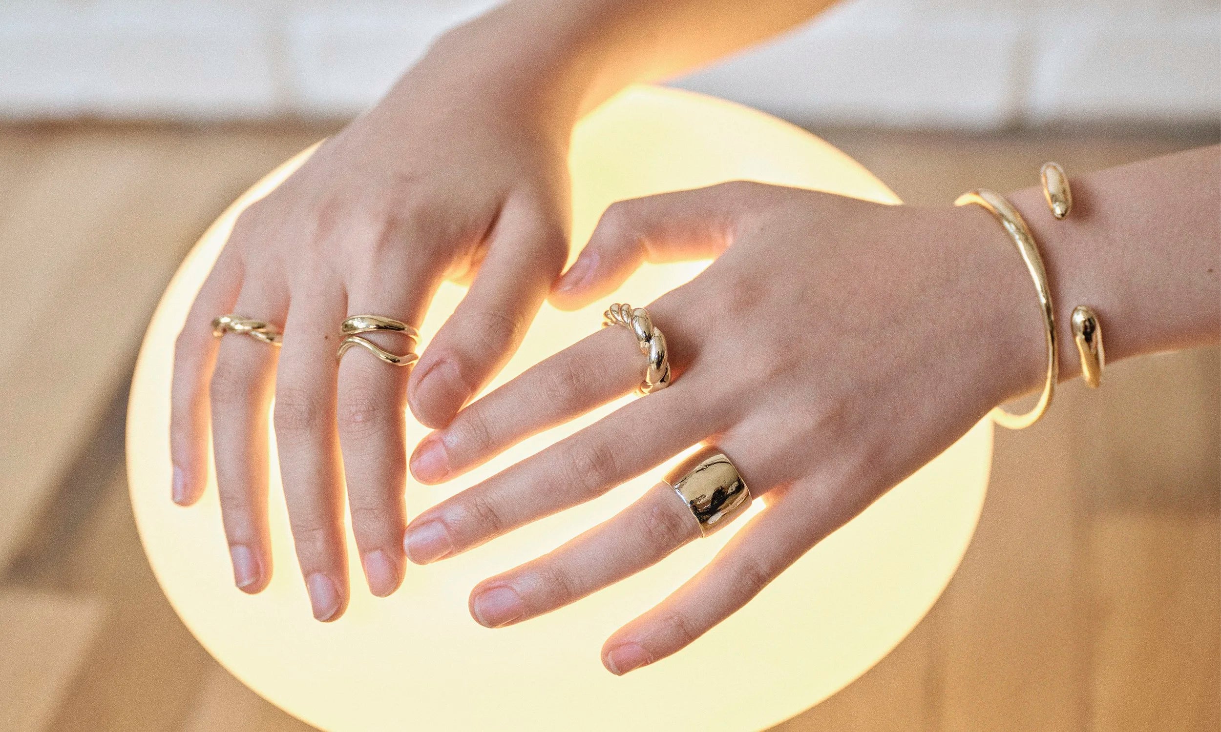 Model Rachel wears the Helix Band, Portal Ring, and the Shapeshifter Ring, along with the Helix Dome Ring, Demeter Cigar Band, Portal Bracelet and Inverse Cuff. Each piece is hand-sculpted and created in solid recycled 14k gold by Talisman Fine Jewelry.