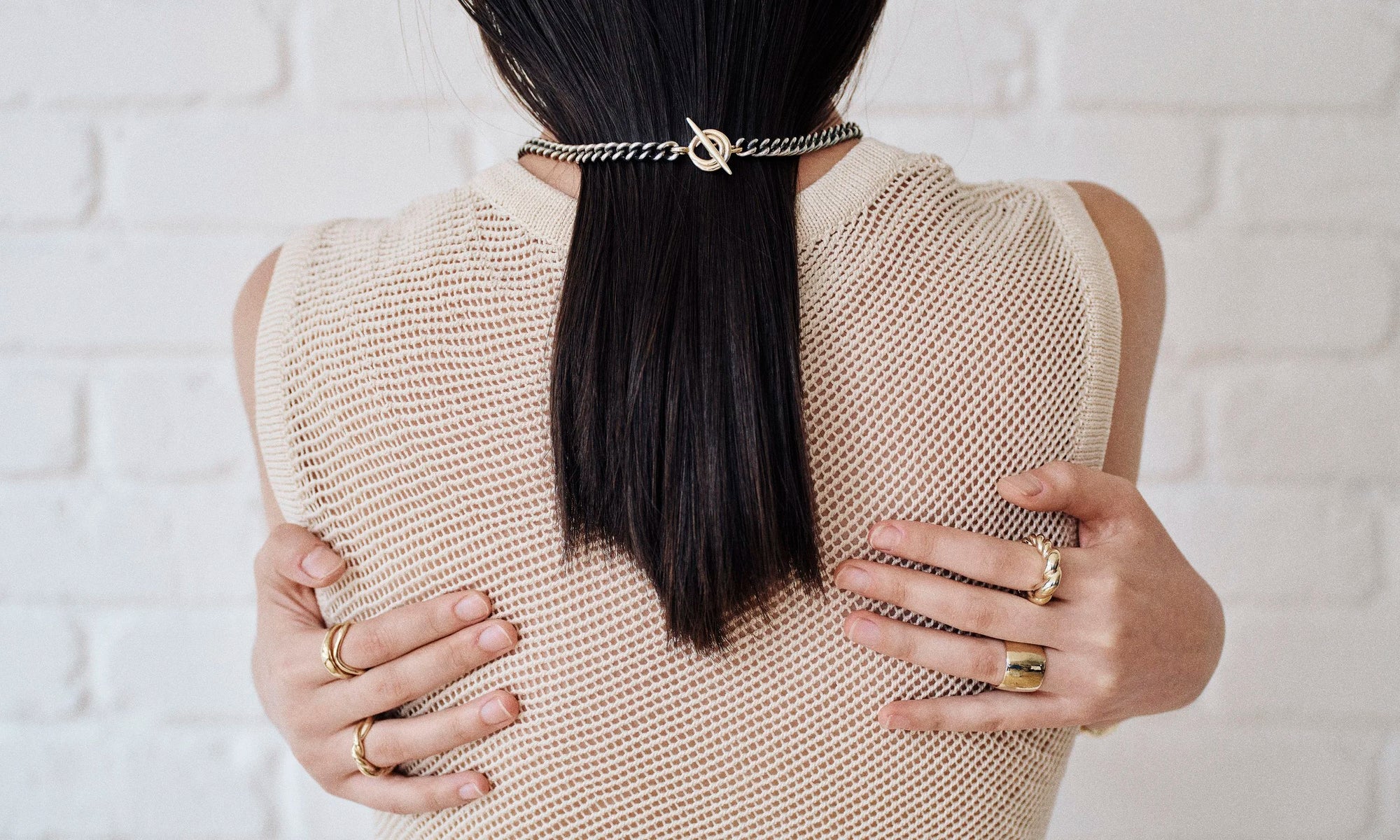 Model Rachel wears the two-tone Vortex Chain, along with the Helix Band, Portal Ring, Shapeshifter Ring, Helix Dome Ring, and Demeter Cigar Band. All sustainably handmade in solid recycled 14k gold and sterling silver.