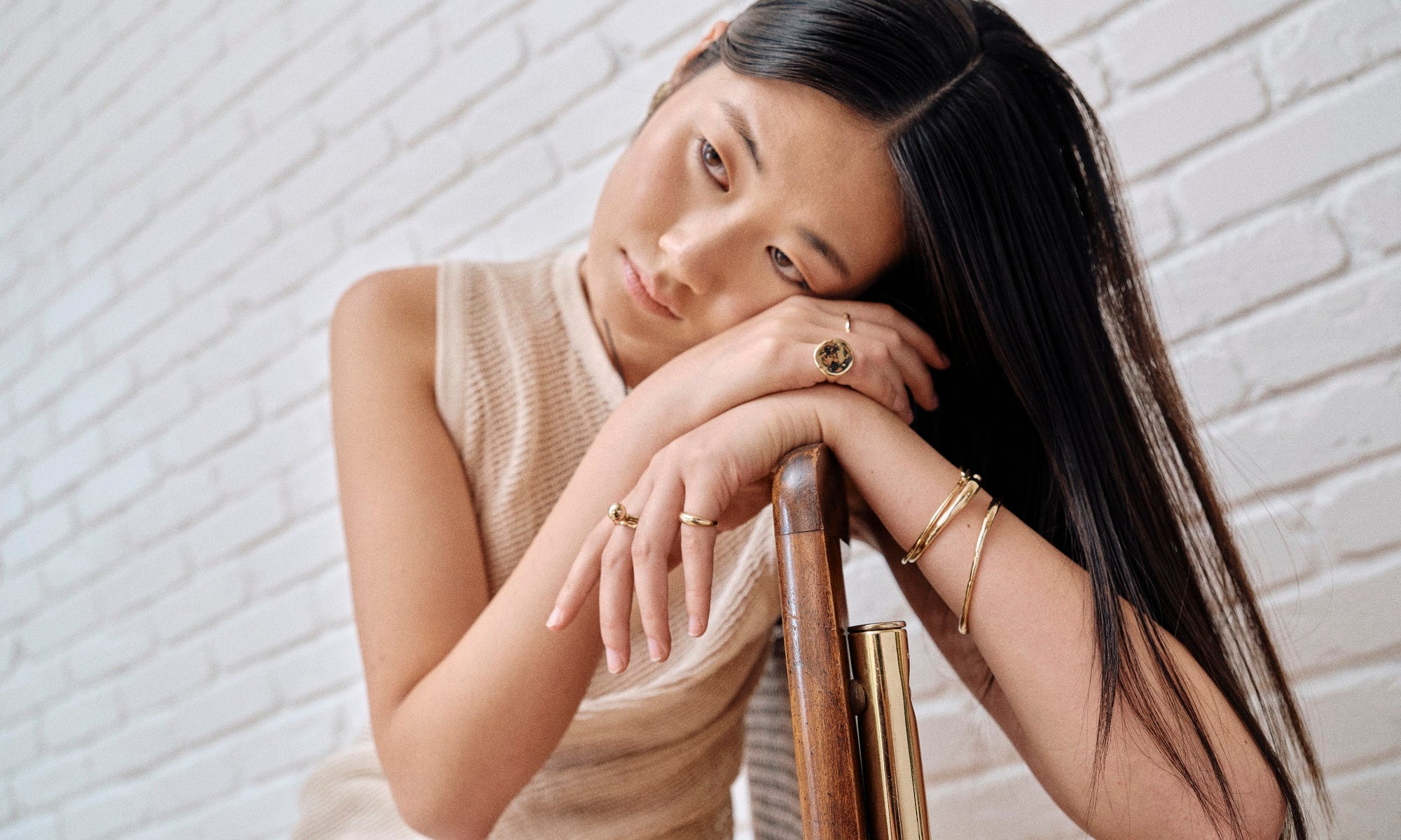 Model Rachel wears the Ouroboros Ring and Ra Pinky Signet, along with the Central Sun Ring, Petite Helix Band, Portal Ring as a pinky ring, Orbit Bracelet, Portal Bracelet and Inverse Cuff. All sustainably handmade in solid recycled 14k gold by Talisman Fine Jewelry.