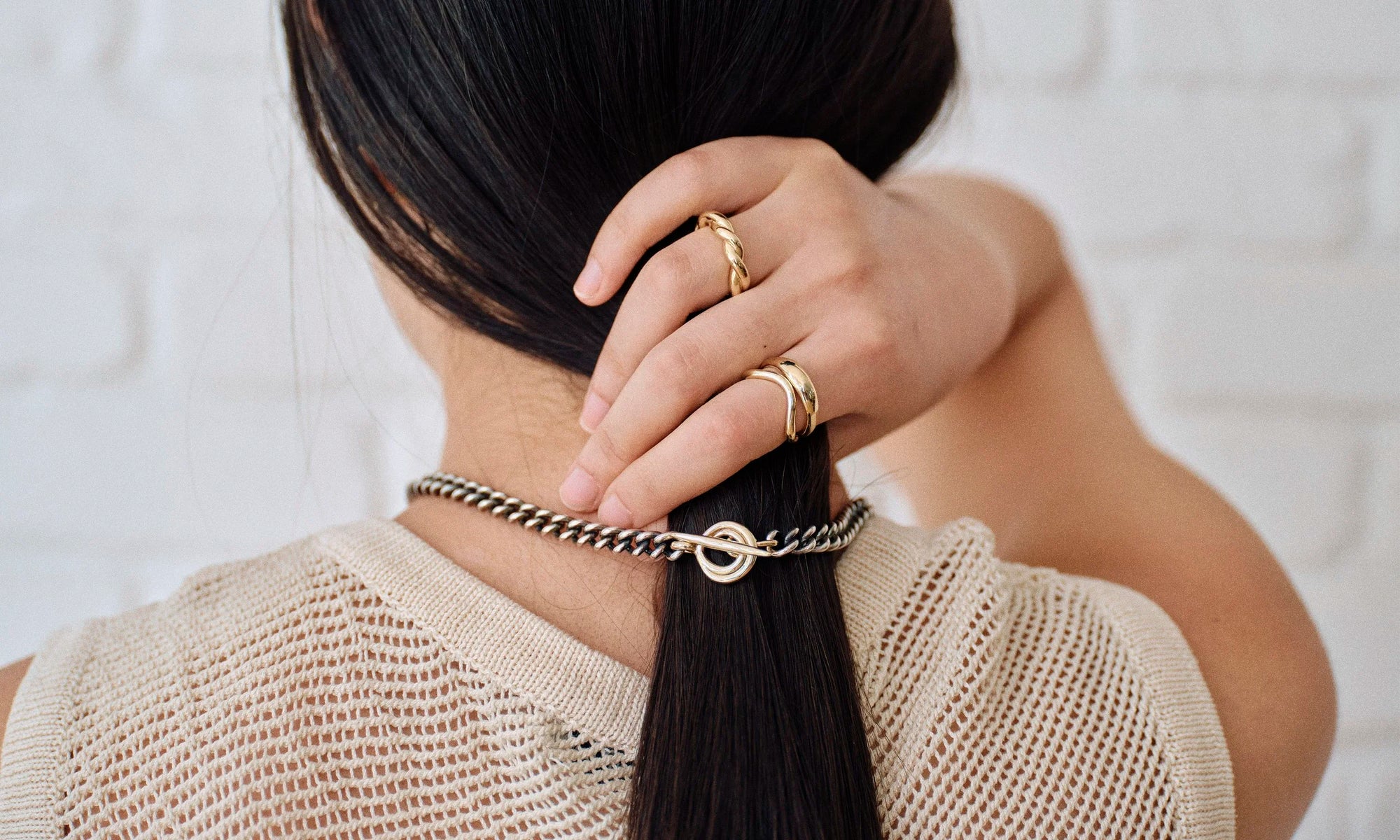 Model Rachel wears the mixed metal Vortex Chain, Portal Ring, Shapeshifter Ring, and Helix Band. Entirely handmade and sculpted out of solid recycled 14k gold and sterling silver.