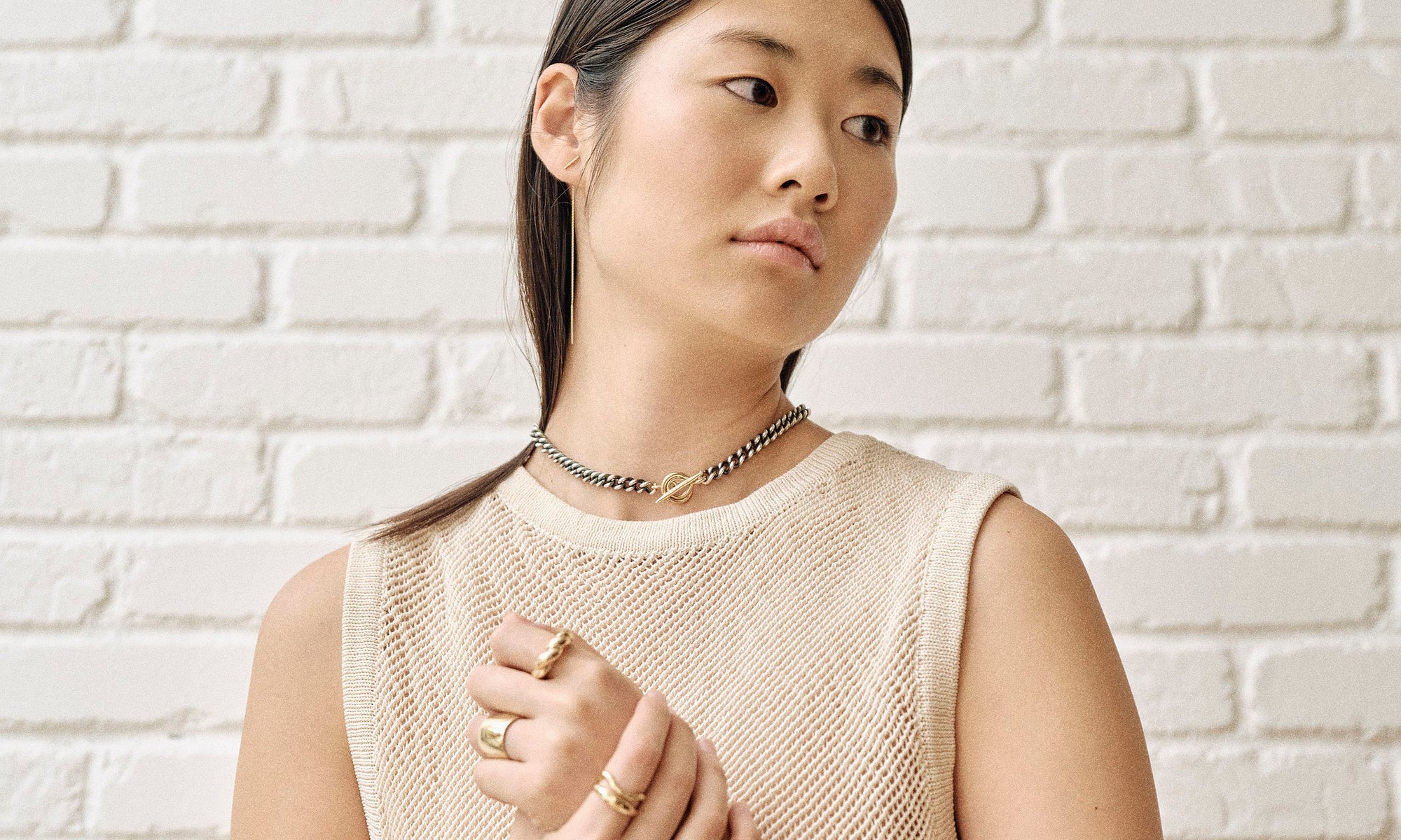 Model Rachel wears the two-tone Vortex Chain, Linear Threader Earring, Demeter Cigar Band, Helix Dome Ring, Shapeshifter Ring, and Portal Ring. All sustainably handmade in solid recycled 14k gold and sterling silver.