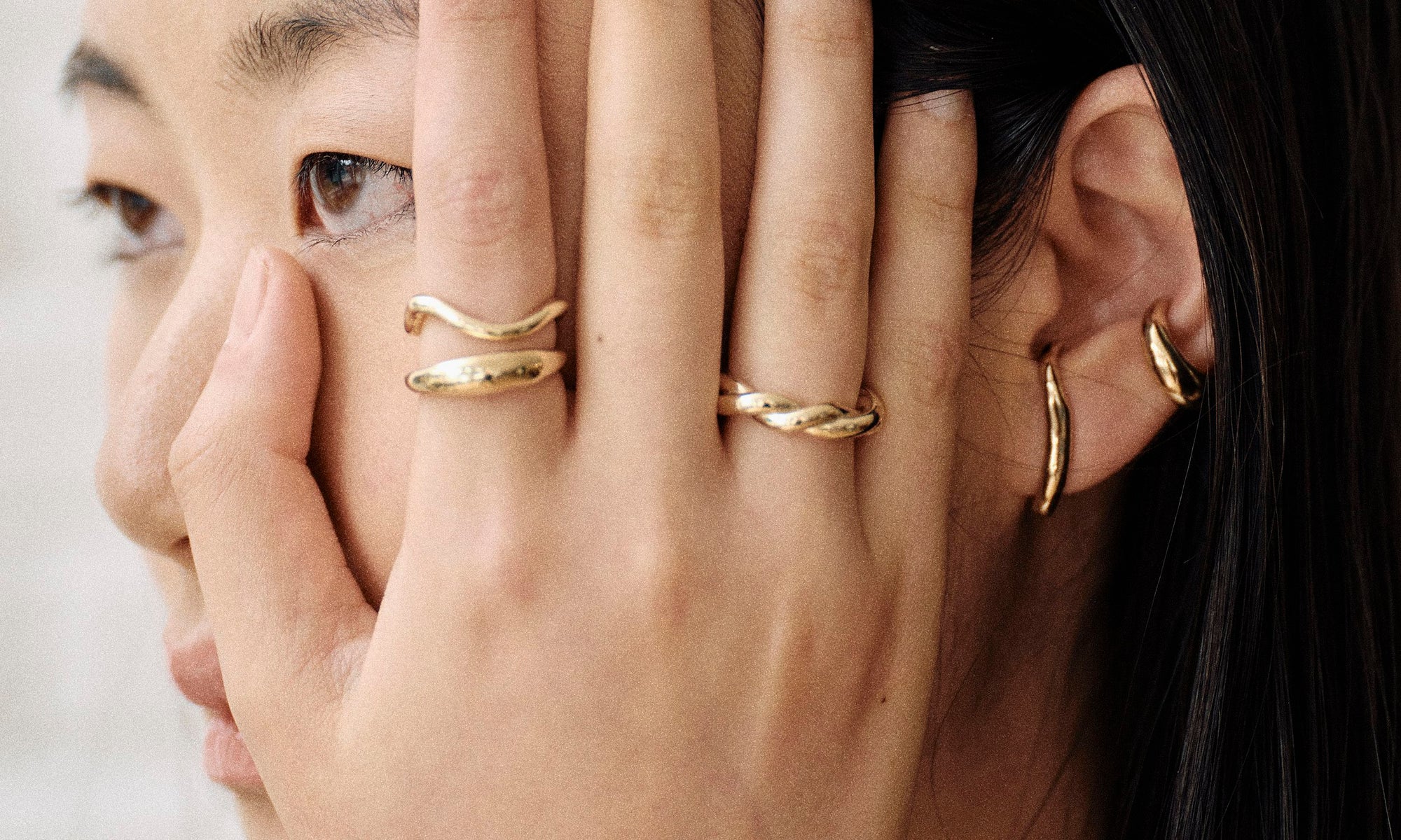 Model Rachel wears the Portal Ring, Shapeshifter Ring, Helix Band, Embrace Earring, and Delphi Ear Cuff. All sustainably handmade in solid recycled 14k gold by Talisman Fine Jewelry.