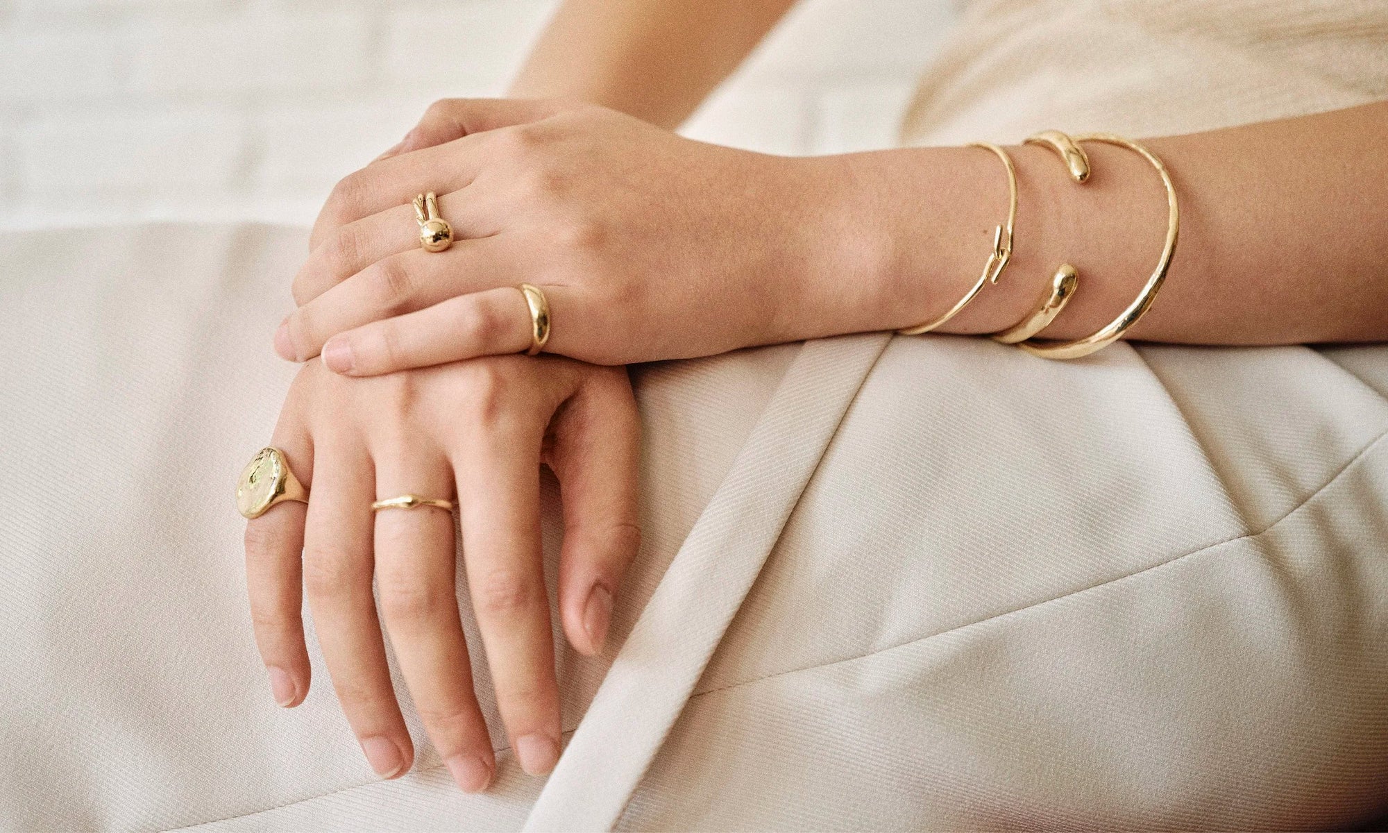 Model Rachel wears the Ra Pinky Signet Ring, Ouroboros Ring, Petite Helix Ring, Central Sun Ring, and Portal Ring paired with the Orbit Bracelet, Inverse Cuff, and Portal Bracelet. Each piece is hand sculpted and created in solid recycled 14k gold by Talisman Fine Jewelry.