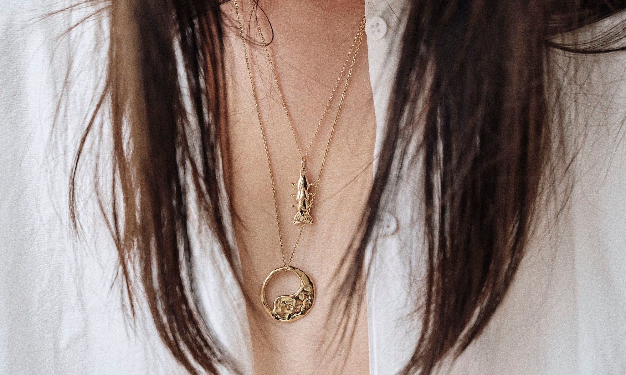 Model Rachel wears the Piscean Dream Necklace and the Yin Yang Necklace. Each pendant is handmade from sustainably sourced solid 14k gold and strung on a gold chain.
