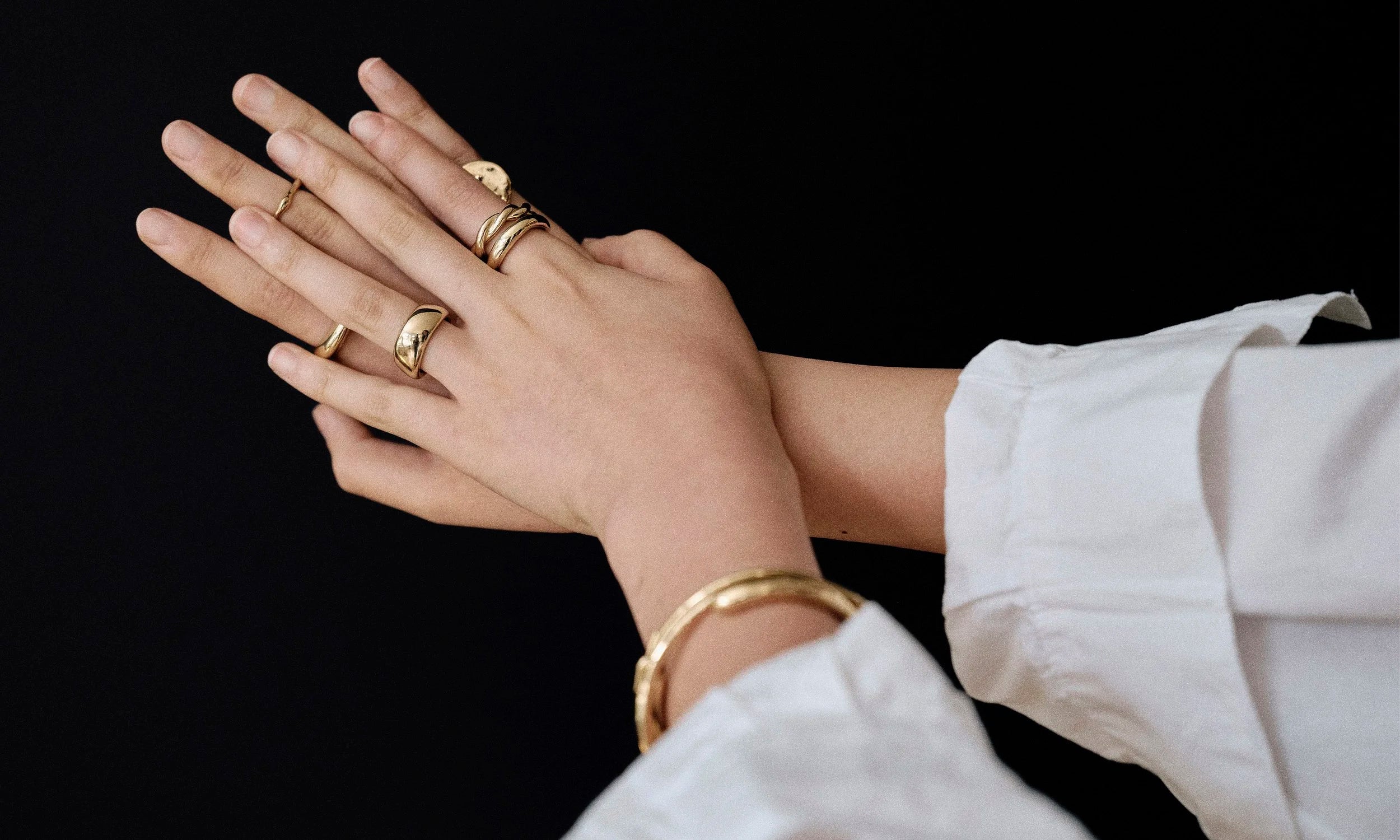 Model Rachel wears Ouroboros Ring, Rollo Band Ring, Helix Band, and Conjunct Cigar Band paired with the Portal Bracelet and Orbit Bracelet. All sustainably handmade in solid recycled 14k gold by Talisman Fine Jewelry.