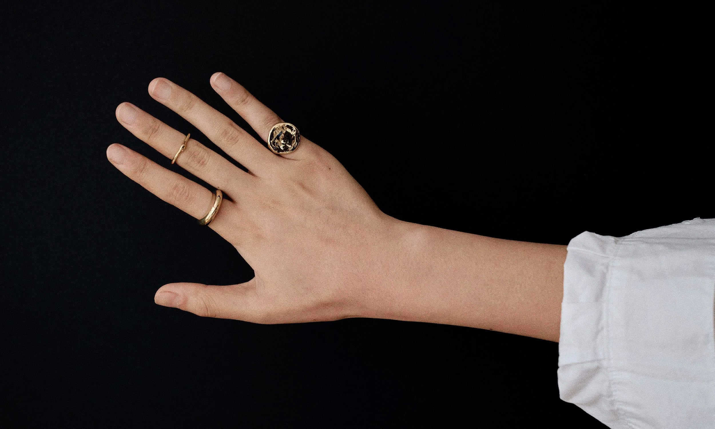 Model Rachel wears the Ra Pinky Signet Ring, Ouroboros Ring, and Persephone Ring. Rings are hand-sculpted and made from ethically sourced recycled 14k gold.