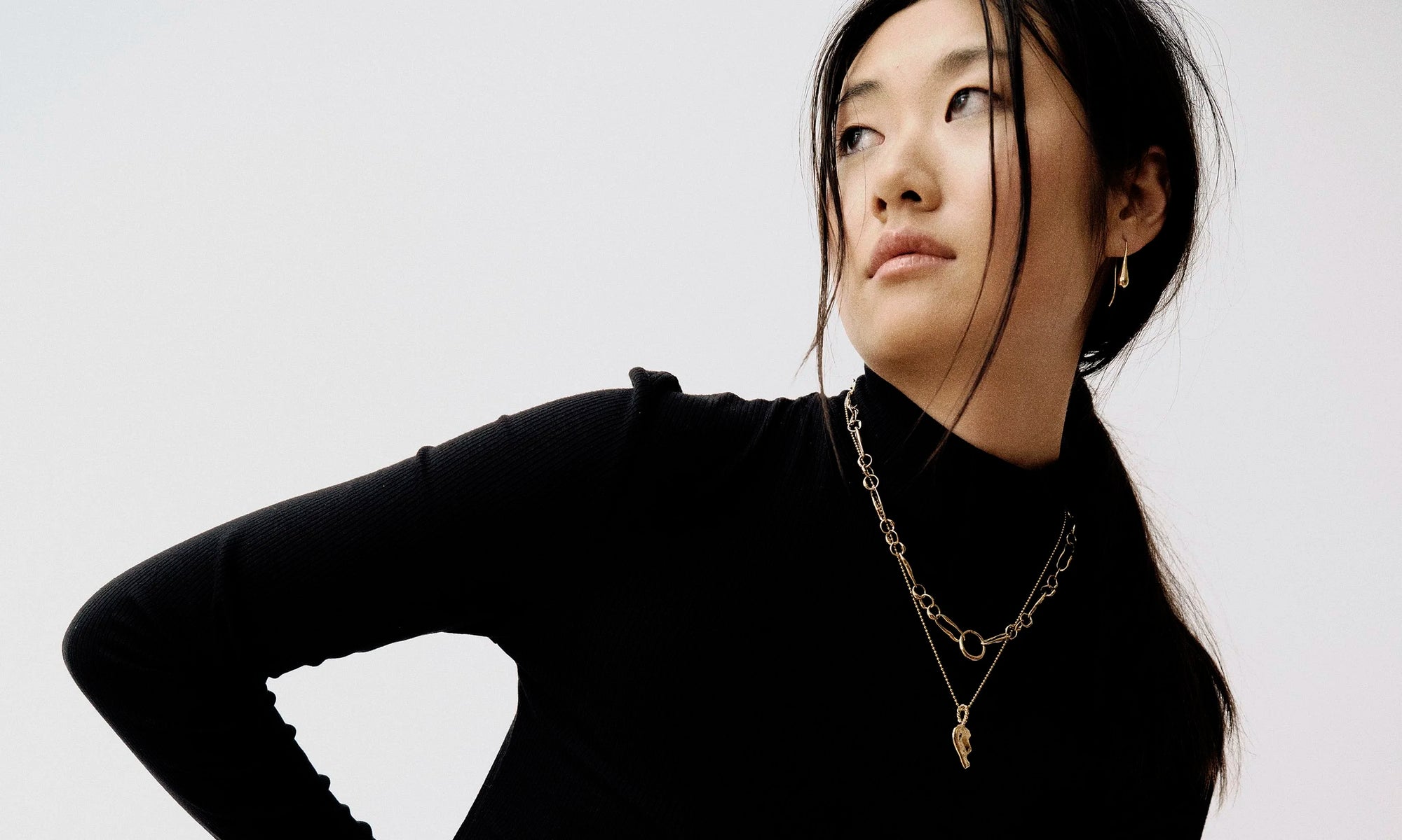 Model Rachel wears the Sanguine Drop Earrings, Metanoia Chain, and the Left BFF Necklace. All sustainably handmade in recycled 14k gold by Talisman Fine Jewelry.