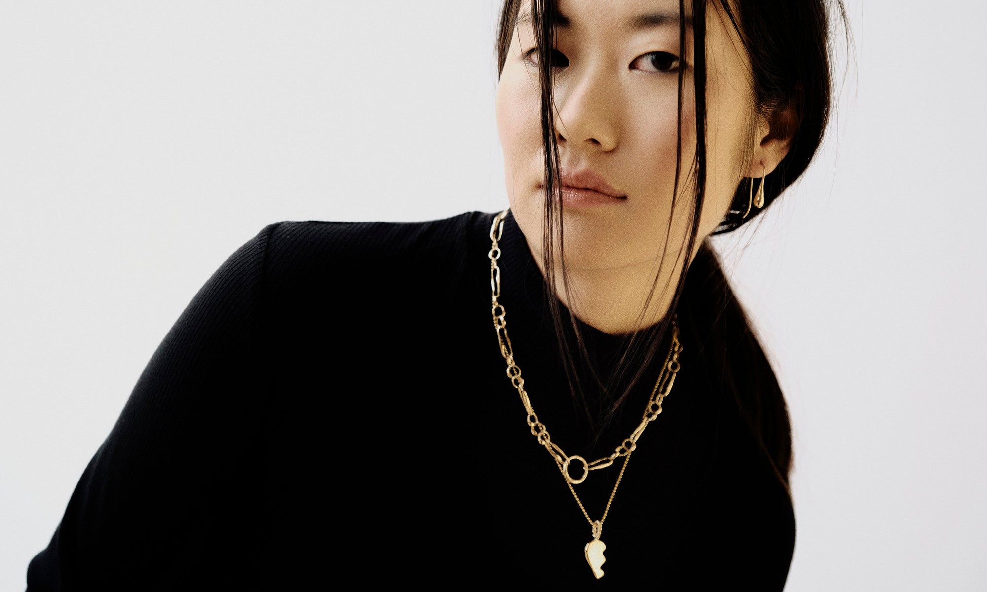 Model Rachel wears the Sanguine Drop Earrings, Metanoia Chain, and the Left BFF Necklace. All sustainably handmade in recycled 14k gold by Talisman Fine Jewelry.