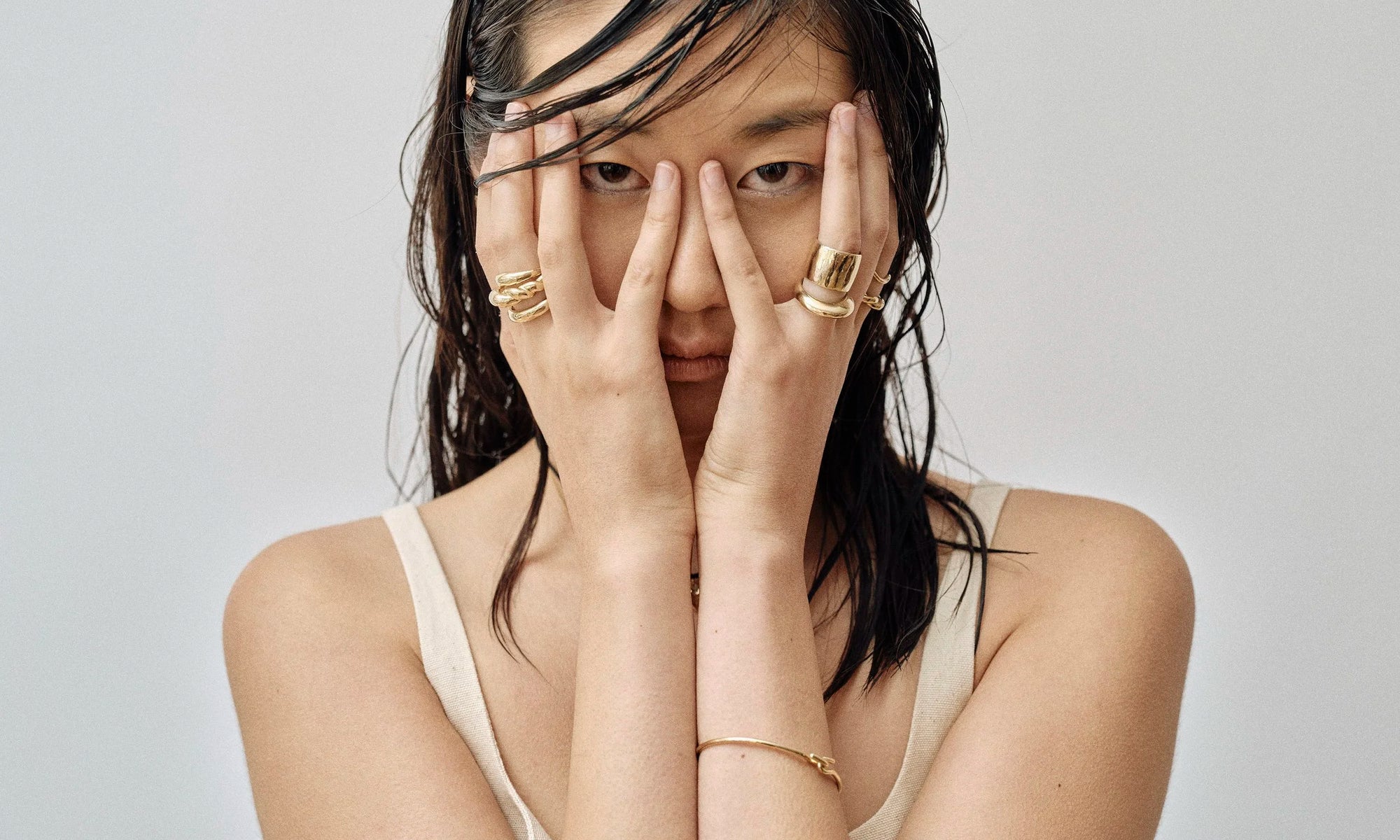 Model Rachel wears the Portal Ring, Helix Dome Ring, Rollo Band Ring, Demeter Cigar Band, Persephone Ring, and Orbit Bracelet. All sustainably handmade in solid recycled 14k gold by Talisman Fine Jewelry.