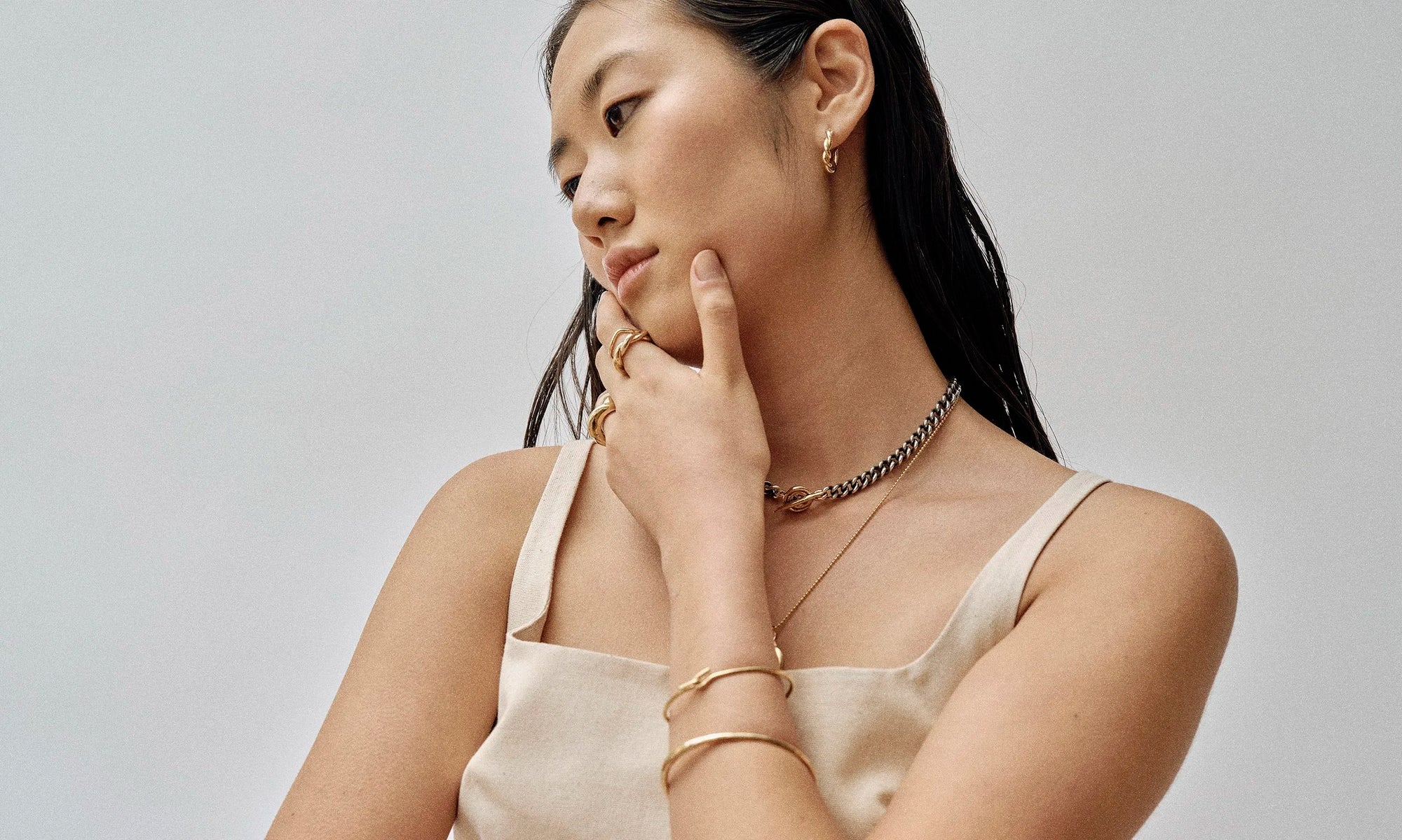 Model Rachel wears the Helix Hoops, two-tone Vortex Necklace, as well as the Orbit Bracelet, Portal Bracelet, Wave Theory Ring, Helix Band, and Persephone Ring. All sustainably handmade in recycled 14k gold by Talisman Fine Jewelry.