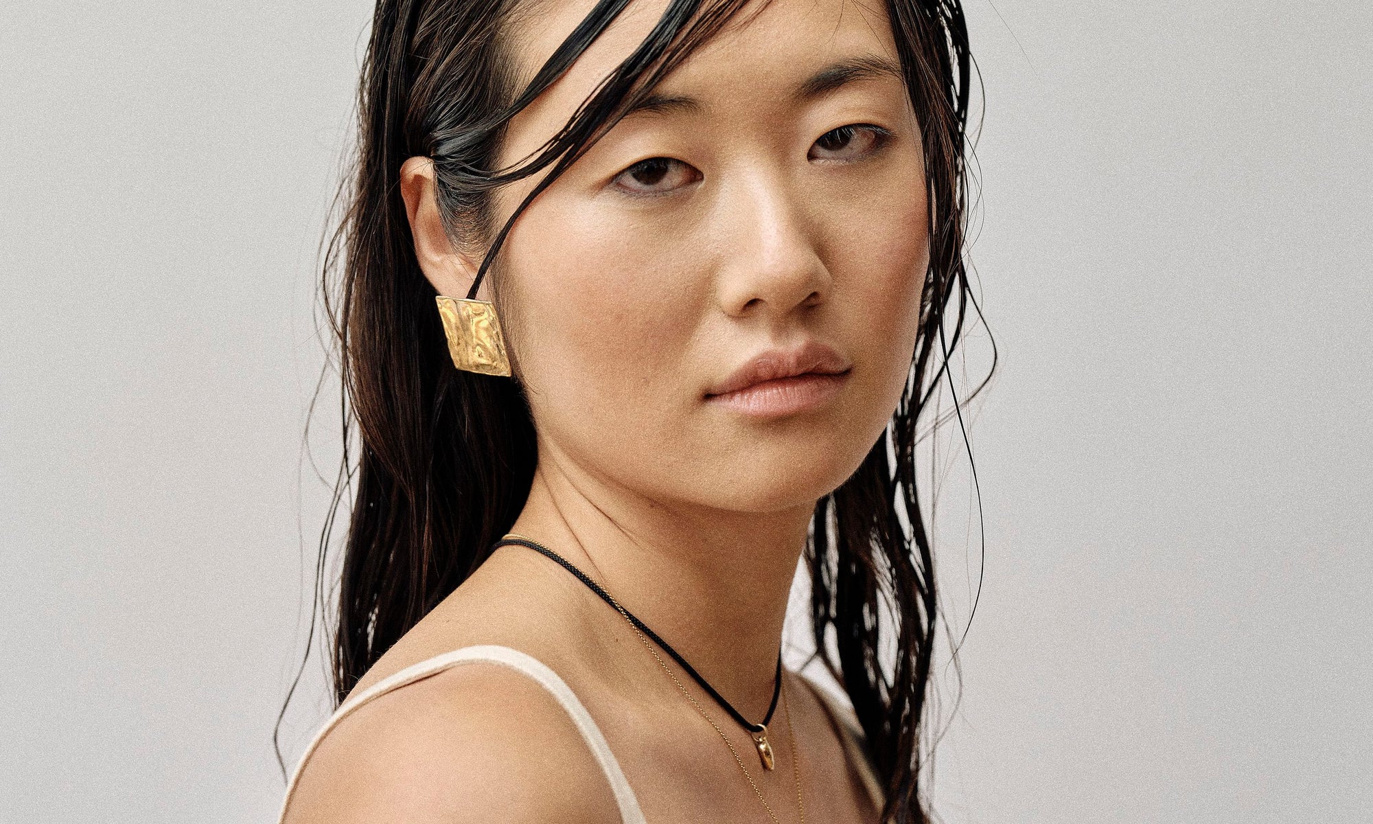 Model Rachel wears the Plane Earrings and Zoe's Heart Necklace on a silk cord. All sustainably handmade in recycled 14k gold by Talisman Fine Jewelry.