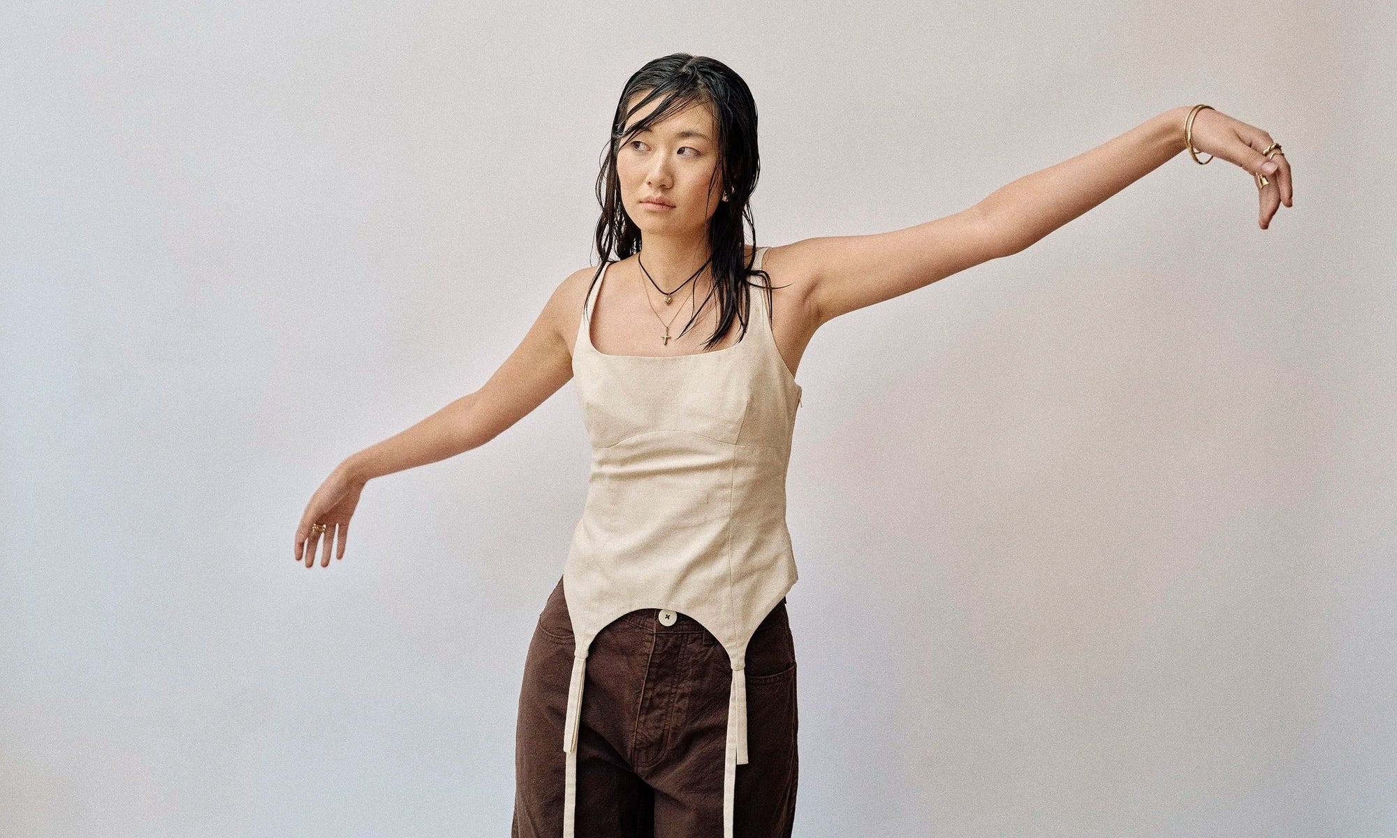 Model Rachel wears the Zoe's Heart Necklace on a silk cord and Christ Consciousness Necklace, as well as the Orbit Bracelet, Portal Bracelet, Wave Theory Ring, Helix Band, and Demeter Cigar Band. All sustainably handmade in recycled 14k gold by Talisman Fine Jewelry.