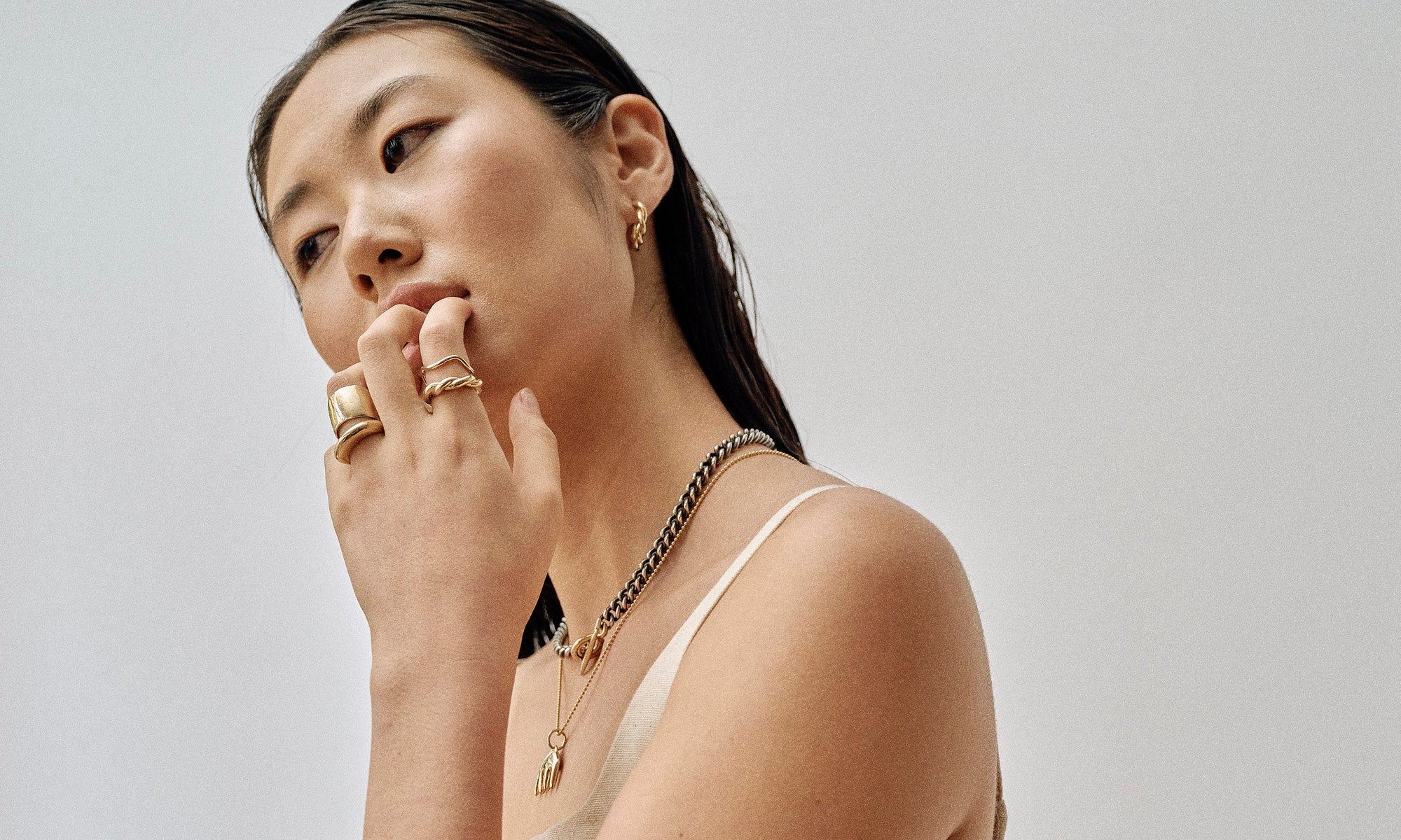 Model Rachel wears the Helix Hoops, two-tone Vortex Necklace, Ariel's Comb Necklace, as well as the Demeter Cigar Band, Persephone Ring, Wave Theory Ring, and Helix Band. All sustainably handmade in recycled 14k gold by Talisman Fine Jewelry.