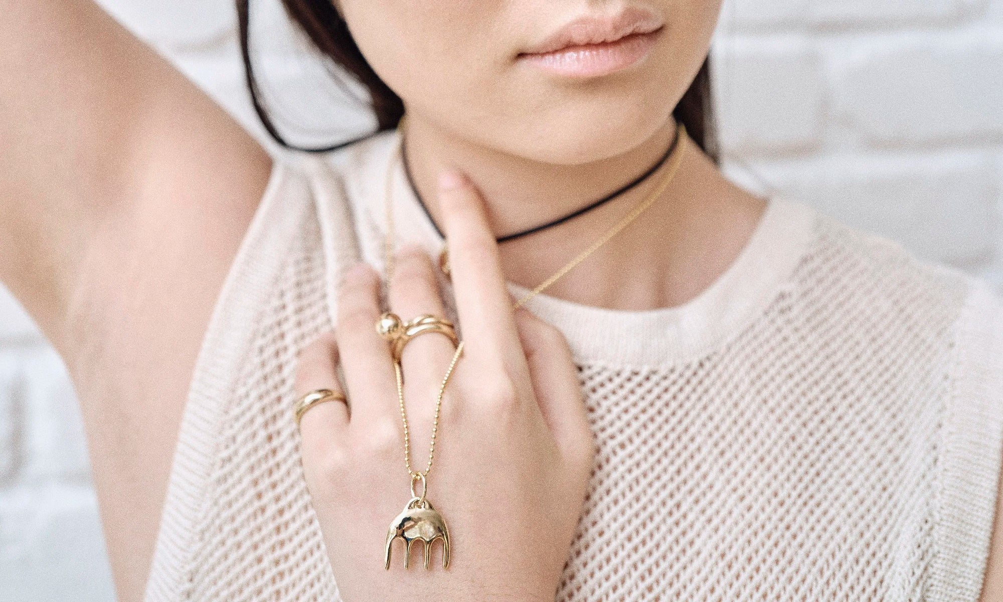 Model Rachel wears the Ariel's Comb Necklace, Portal Ring, Petite Helix Band, and Central Sun Ring. Each piece is hand sculpted from solid recycled 14k gold.