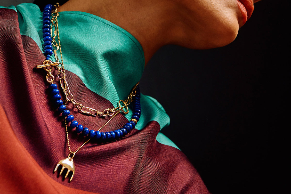 Thaiara wears the Metanoia Chain, Prayer Necklace in Lapis, and Ariel's Comb Necklace, layered together to highlight contrasting textures and color.