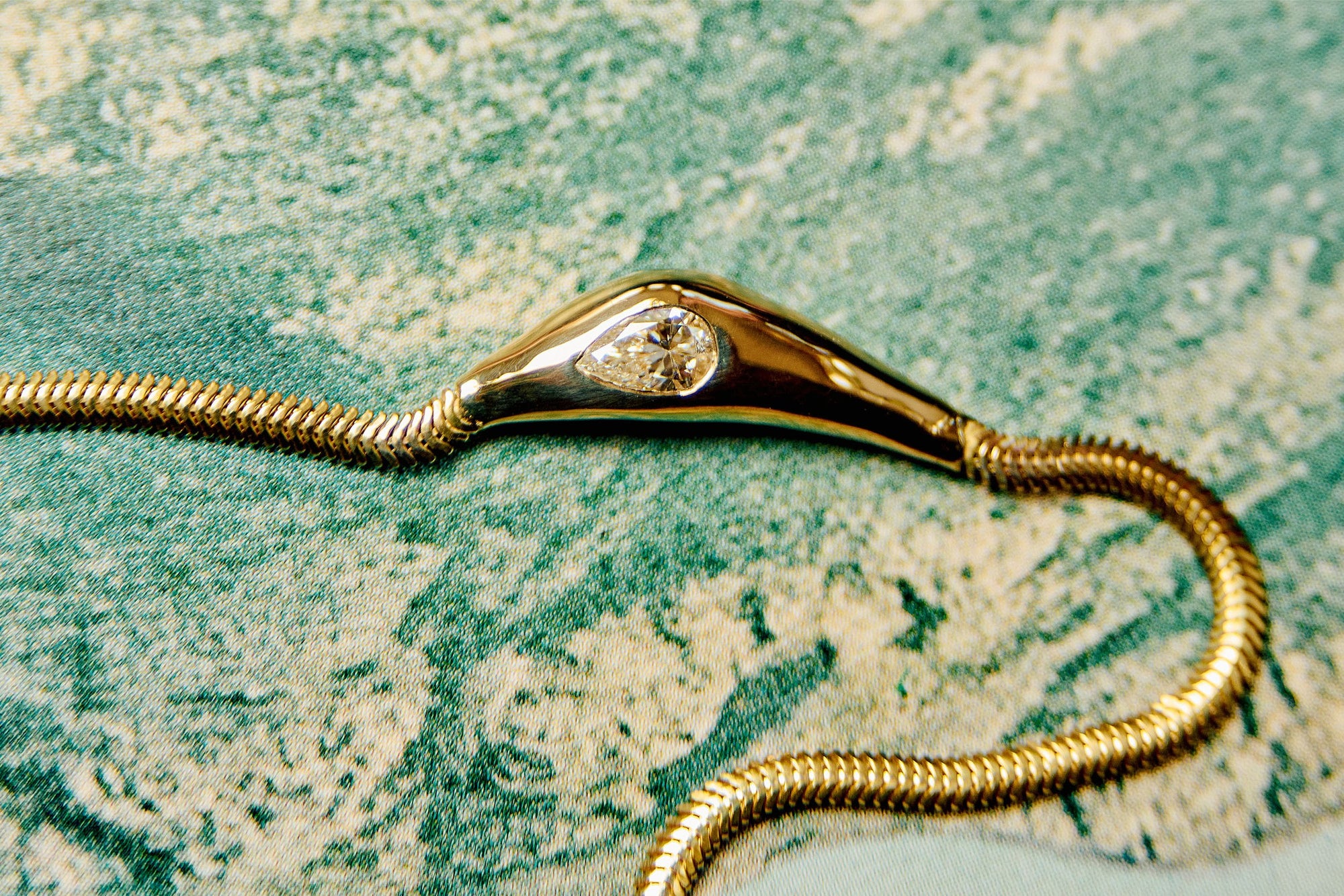 This Fall-Winter's signature piece, the Where the Light Comes Through Necklace. A handmade necklace featuring a wide snake chain with a molten gold form, flush set with a sparkling pear-cut diamond.