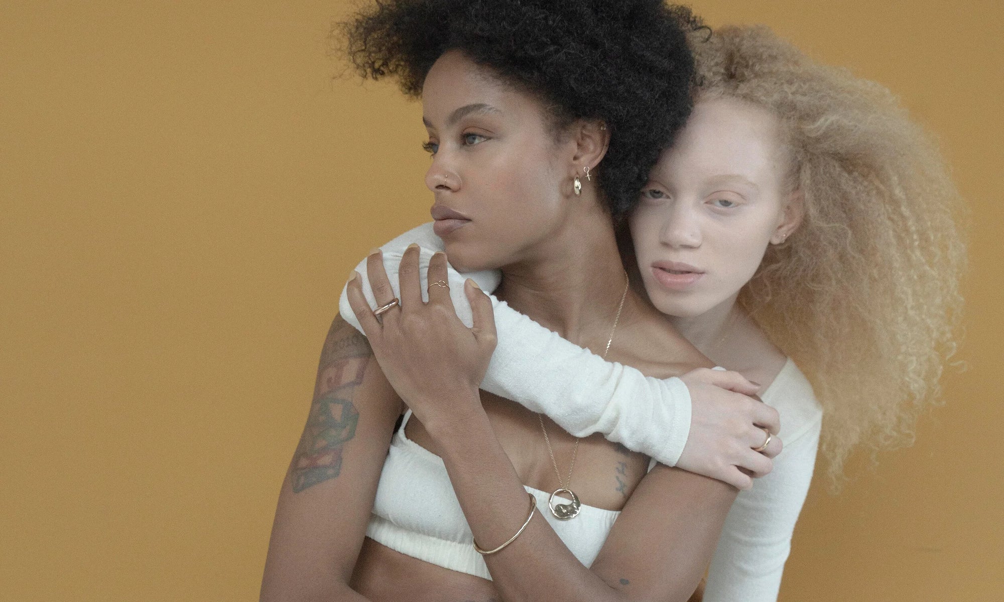 Models Alicia Myers and Nyasia Wyani wear Talisman's latest collection. In this photo, clockwise from top left: The Persephone Ring, Circle Shape Ring, Rollo Hoops, Venus Stud, Mini Rainbow Stud, Rollo Band, Yin Yang Necklace, and Portal Bracelet. All sustainably handmade in recycled 14k gold.