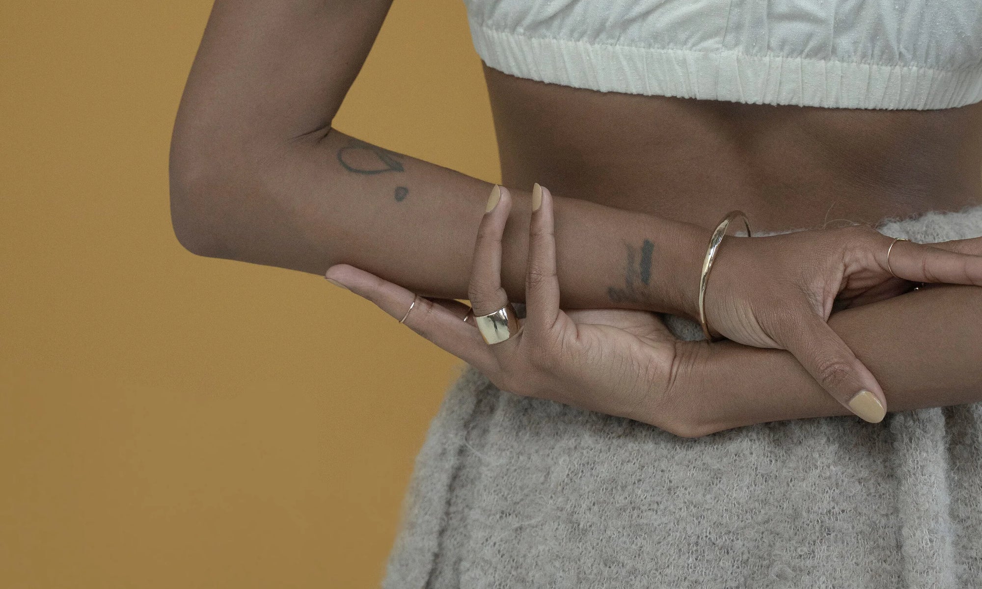 Model Alicia Myers wears the Goldyn Hammered Stacking Band, Demeter Cigar Band, Portal Bracelet and Circle Shape Ring. All sustainably handmade using lost-wax casting techniques, in recycled 14k gold.