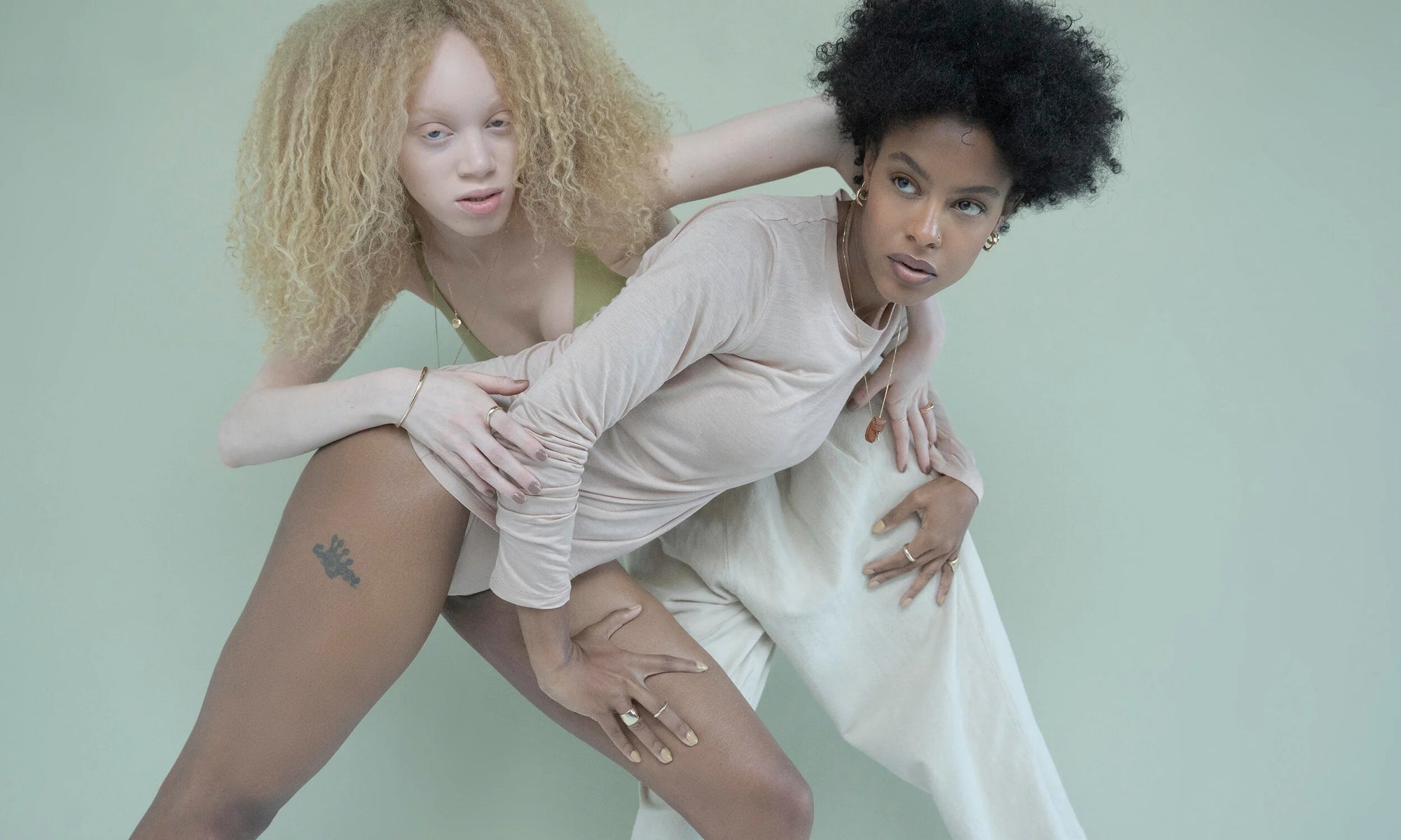 Models Alicia Myers and Nyasia Wyani stand guard in the Talisman Fine Jewelry Alchemy Collection. Counterclockwise from left: The Portal Bracelet, Portal Ring, Demeter Cigar Band, Petite Rollo Band, Rollo Band, Ra Pinky Signet, Rose Cut Diamond Talisman Pouch Necklace, Persephone Ring, Rollo Hoops, Aphrodite Hugs, and Michael Amulet Necklace. All sustainably handmade in recycled 14k gold, using traditional lost-wax casting techniques.