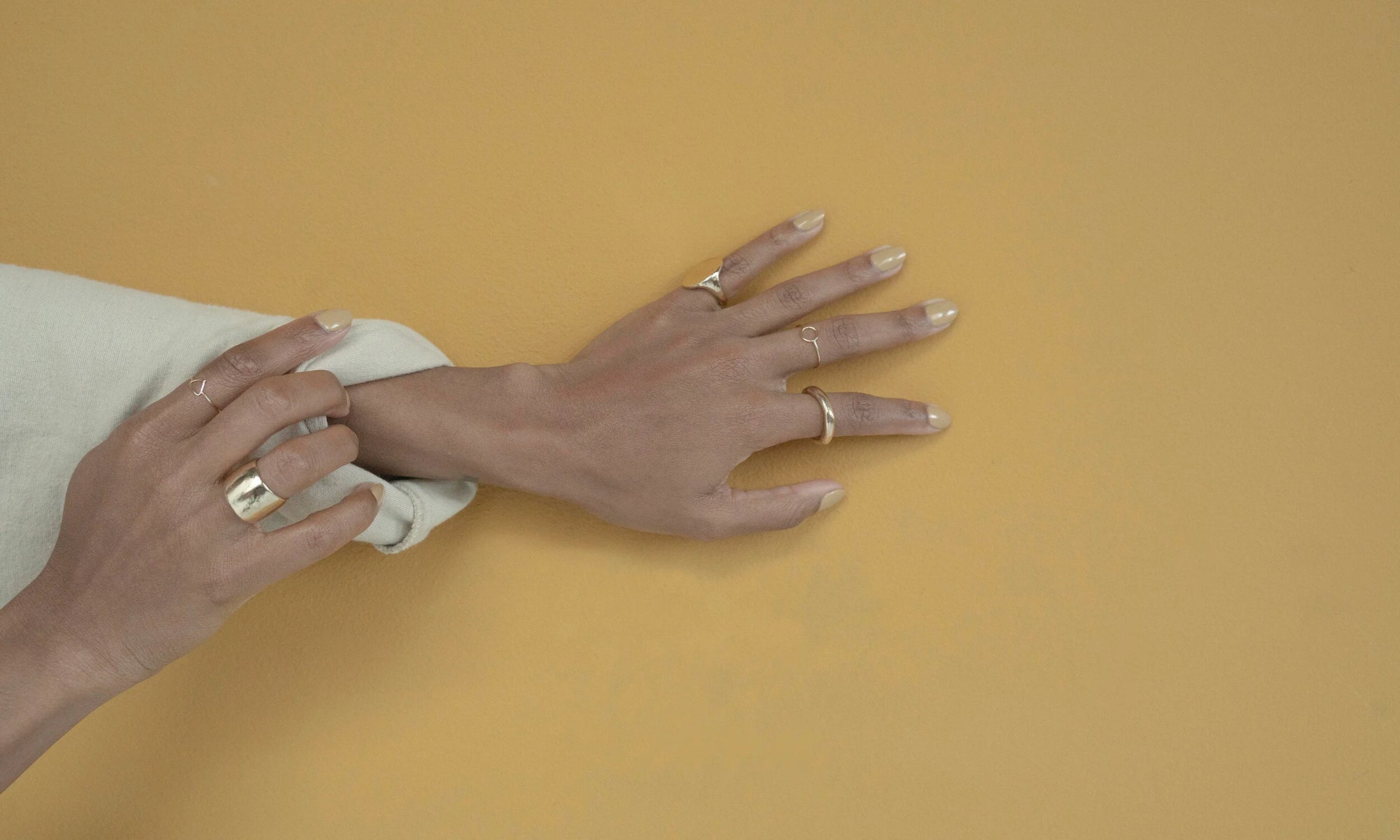 Model Alicia Myers wears Talisman Fine Jewelry, counterclockwise from left: Triangle Shape Ring, Demeter Cigar Band, Rollo Band, Circle Shape Ring, Ra Pinky Signet. All sustainably handmade in recycled 14k gold, using traditional lost-wax casting techniques.