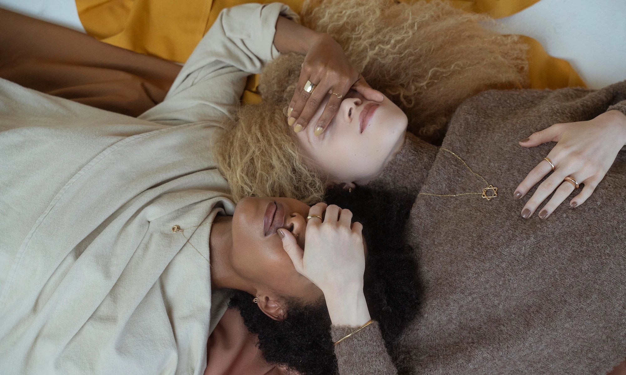 Models Alicia Myers and Nyasia Wyani wear the latest from the Talisman Alchemy Collection. Counterclockwise from left: The Michael Amulet Necklace, Aphrodite Hugs, Peace Sign Stud, Mini Orb Stud, Portal Ring, Portal Bracelet, Solomon's Seal Bracelet, Petite Rollo Band, Persephone Ring, Triangle Shape Ring, and Demeter Cigar Band. All sustainably handmade in recycled 14k gold.