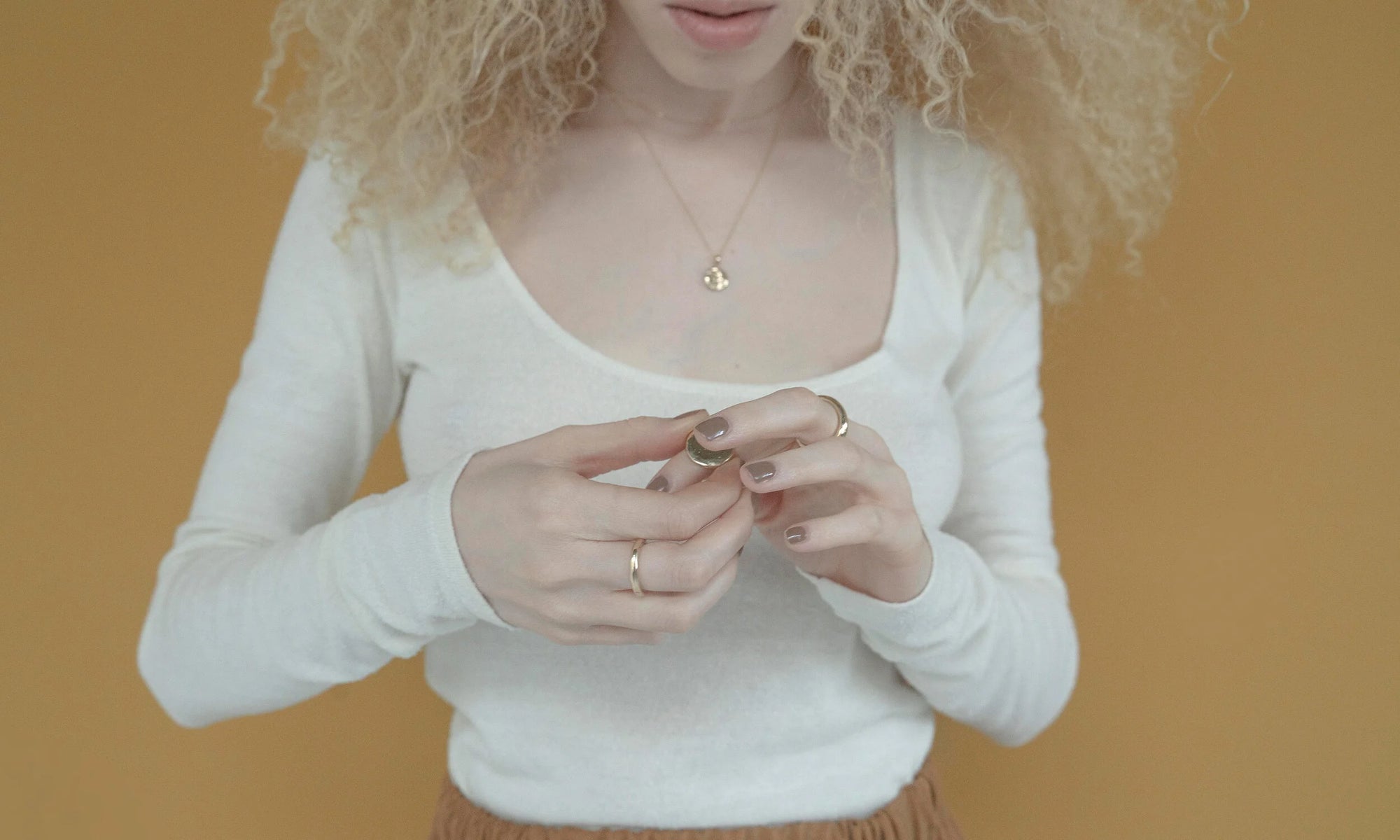 Model Nyasia Wyani wears the Petite Rollo Band, Ra Pinky Signet as a midi ring, Rollo Band, and the Michael Amulet Necklace layered with the Whisper Chain. All sustainably handmade using traditional lost-wax casting techniques, in recycled 14k gold.