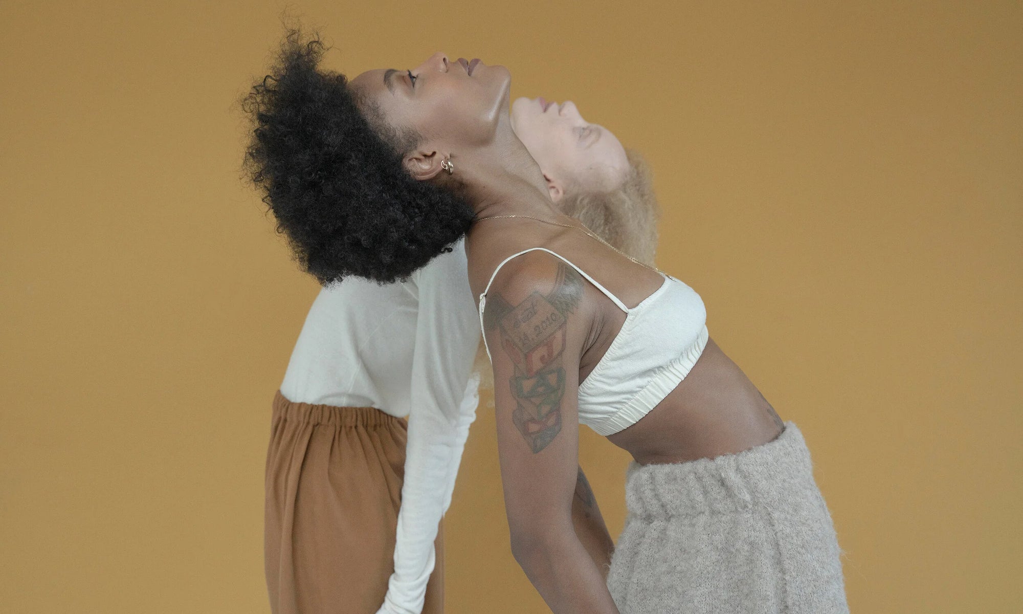 Models Alicia Myers and Nyasia Wyani looking ahead in Talisman Fine Jewelry. Alicia wears the Rollo Hoops and Moon Stud, along with the Yin Yang Necklace. All sustainably handmade in recycled 14k gold.