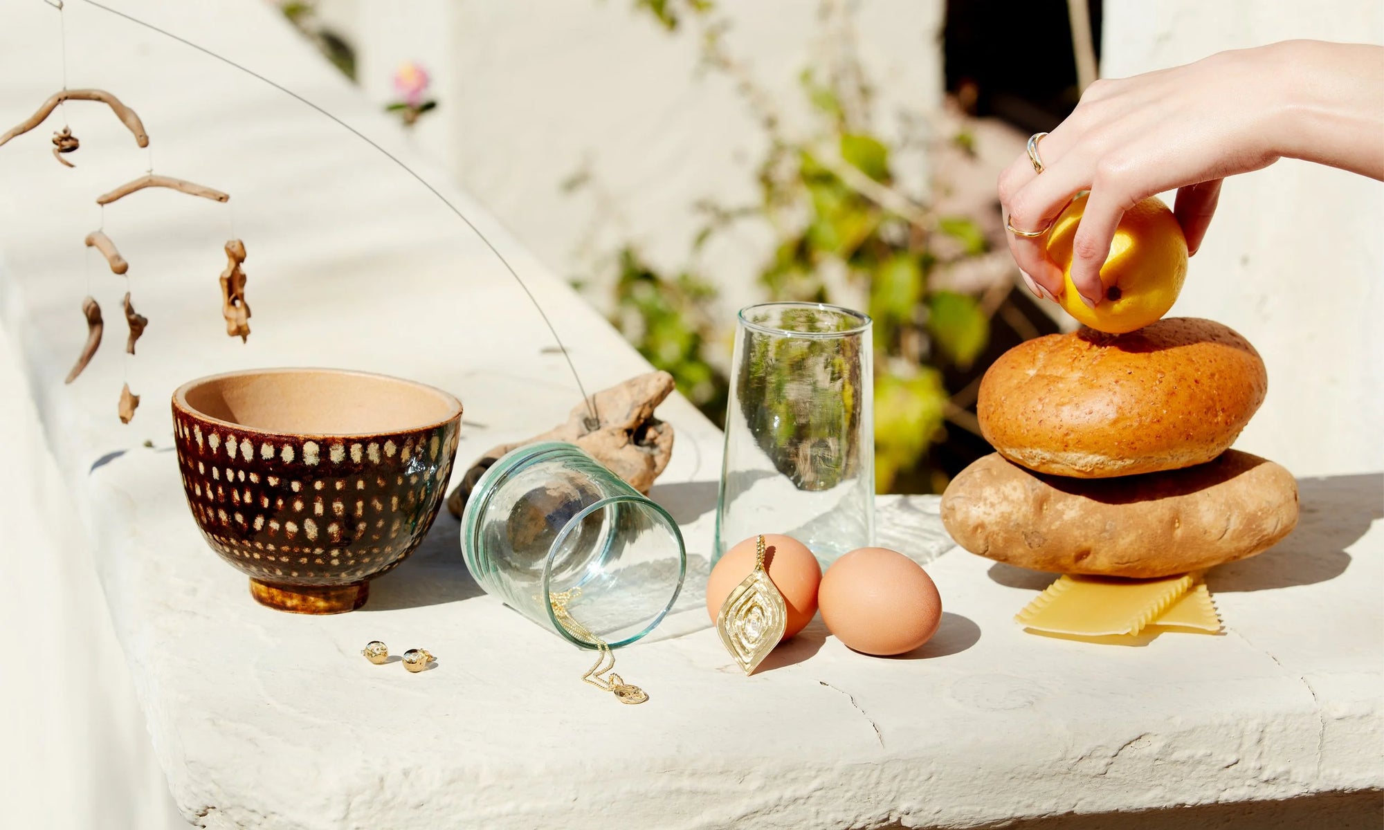 The spread, from left: Central Sun Earrings, Phoenix Amulet Necklace, Mary Pendant, and Alianna Martinez wears the Rollo Band and Sirius A Ring.