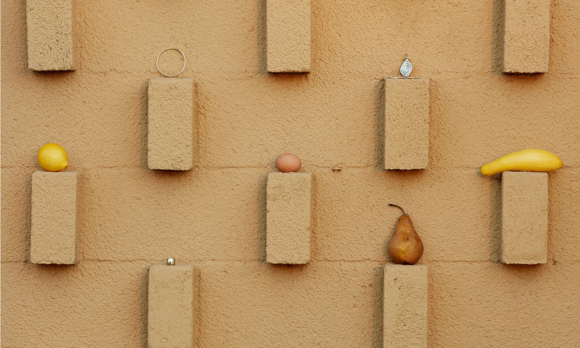 On the wall, clockwise from top left: The Portal Bracelet, the Mary Pendant, and the Demeter Cigar Band. All sustainably handmade in recycled 14k gold.