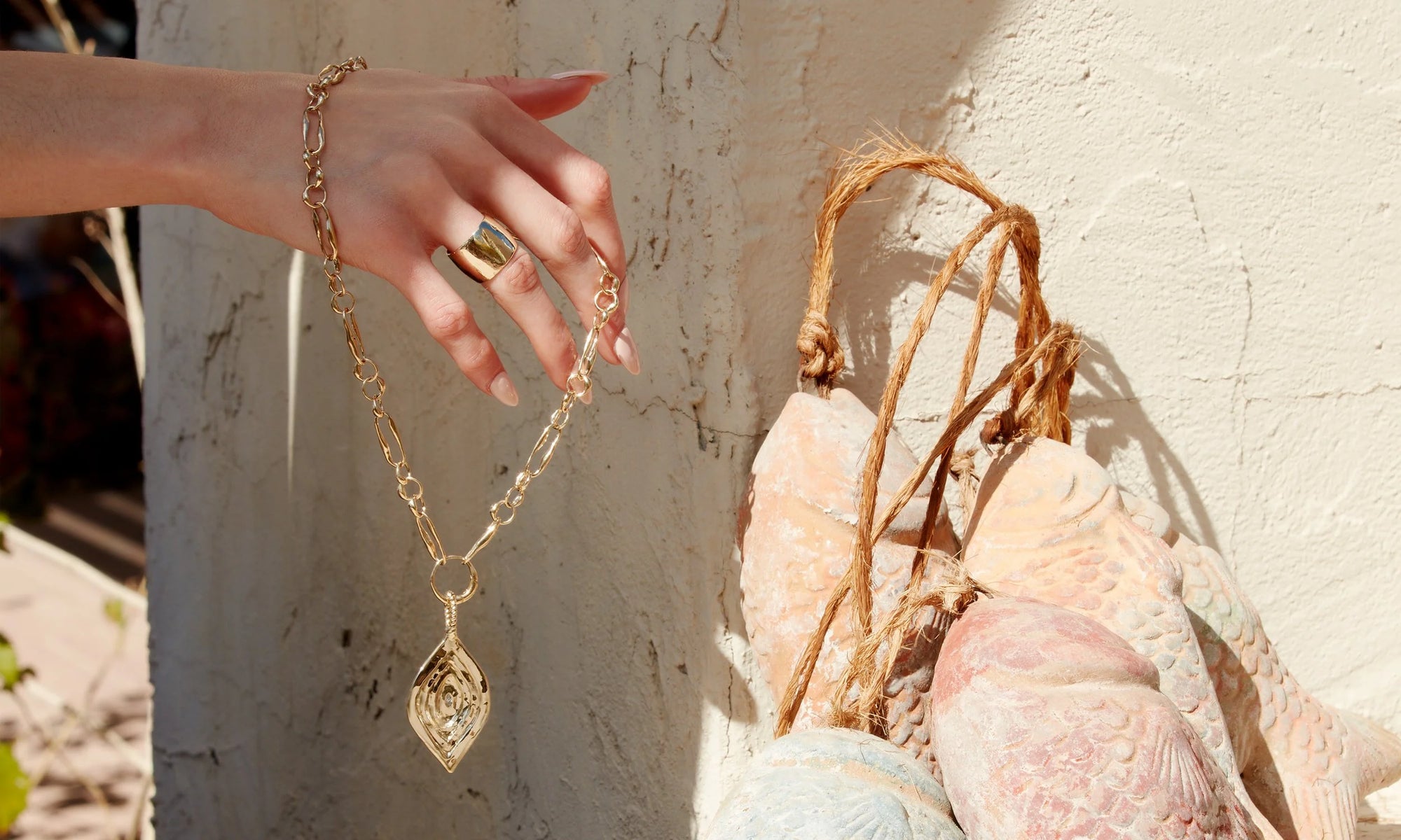 Fresh catch: Alianna wears the Demeter Cigar Band and holds the Metanoia Chain and Mary Pendant Set. All sustainably handmade in solid, recycled 14k gold.