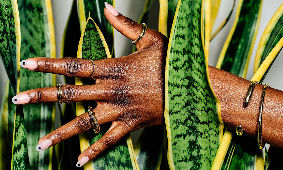 Model Sam wears, from bottom left: the Helix Ring, Infinite Ring Stack, Wave Theory Ring, Rollo Band, and the Inverse Cuff and Portal Bracelet. All sustainably hand-sculpted and cast in recycled 14k gold.