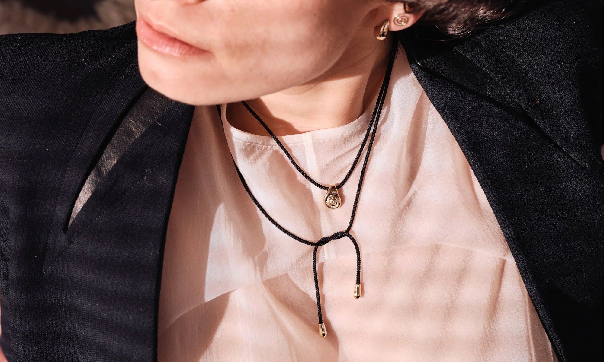 Model Erika wears the Growth Necklace on silk cord, Sanguine Stud Earrings, and Spiral Stud Earring. Entirely handmade from 14k recycled gold.