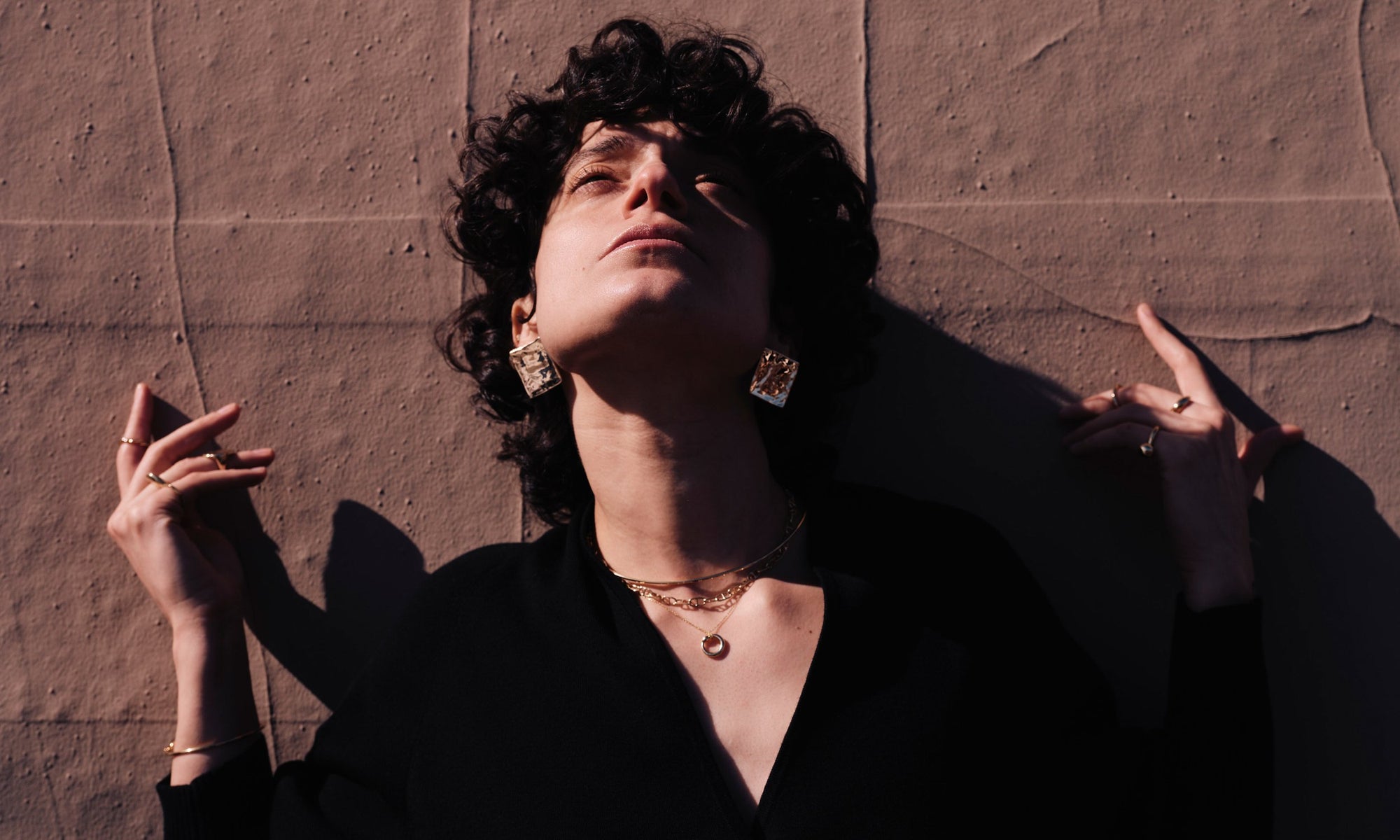 Model Erika wears the Plane Earrings, Orbit Collar, Anchored Handmade Chain, and Ouroboros Necklace. All sculpted and handmade in solid, recycled 14k gold.