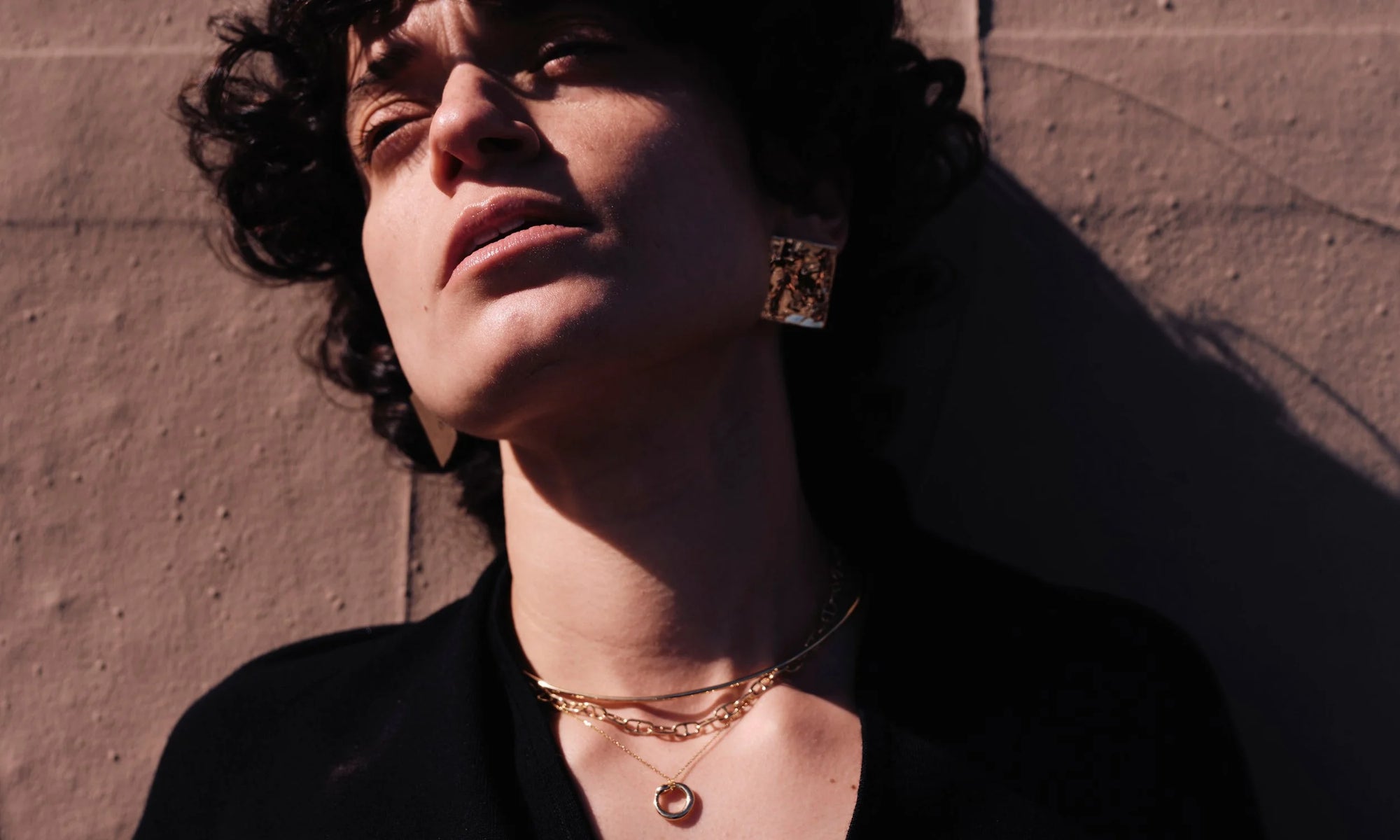 Model Erika Rodriguez wears the Plane Earrings, Orbit Collar, Anchored Handmade Chain, and Ouroboros Necklace. All sculpted and handmade in solid, recycled 14k gold.