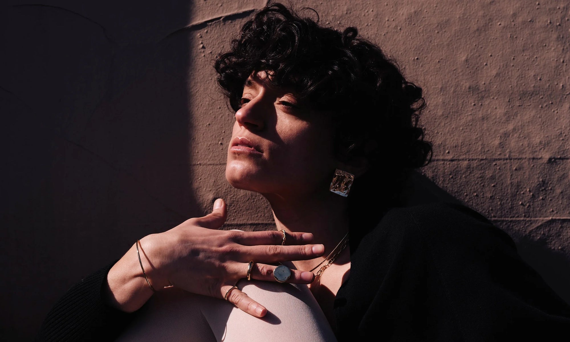 Model Erika Rodriguez wears the Plane Earrings, and from left: Orbit Bracelet, Sirius B Ring, Persephone Ring, Ra Signet, Petite Helix Band, Orbit Collar Necklace, and Anchored Handmade Chain. All sculpted and handmade in solid, recycled 14k gold.